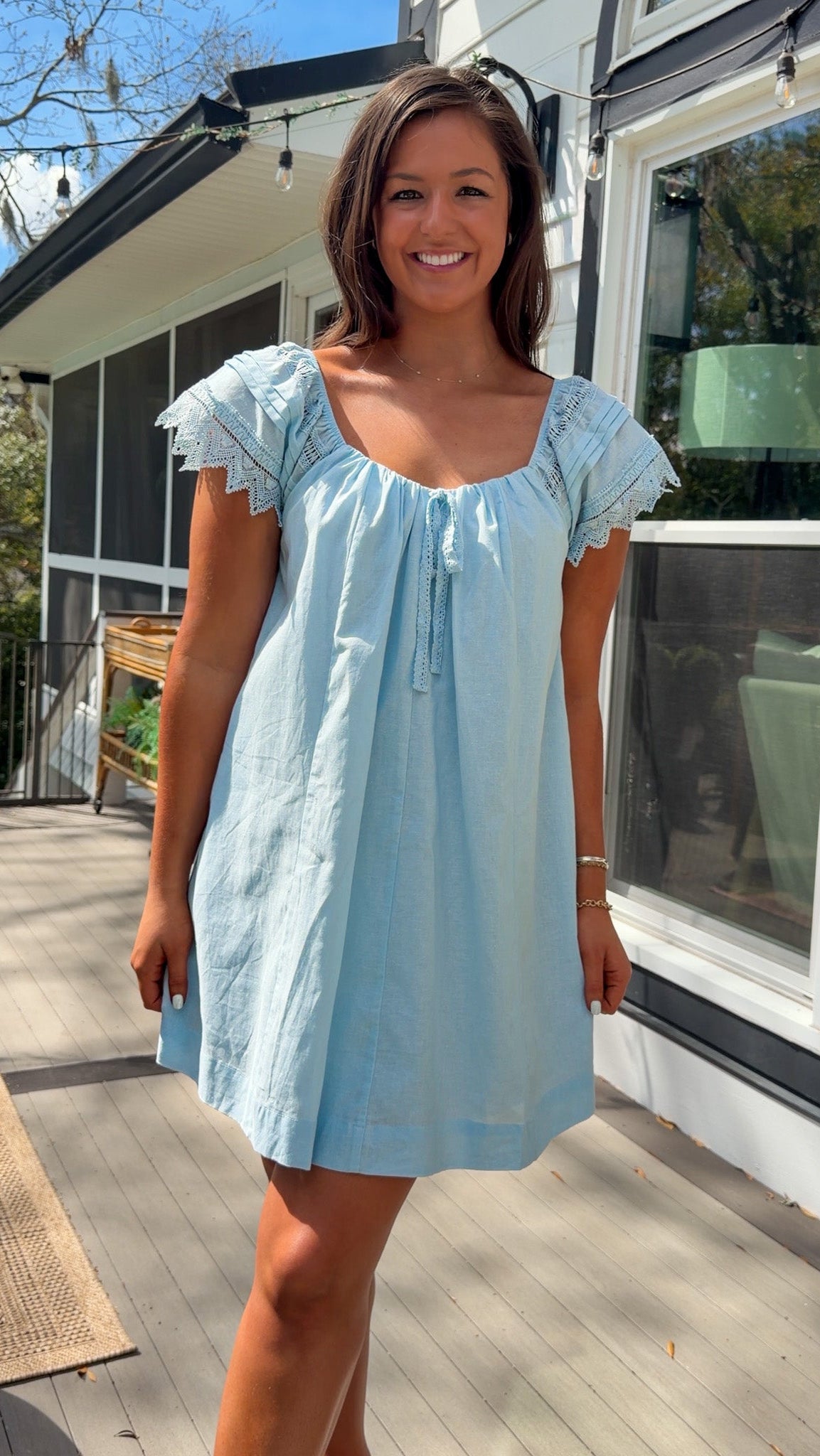 light blue linen blend mini dress with eyelet lace trim sleeves and tie neckline