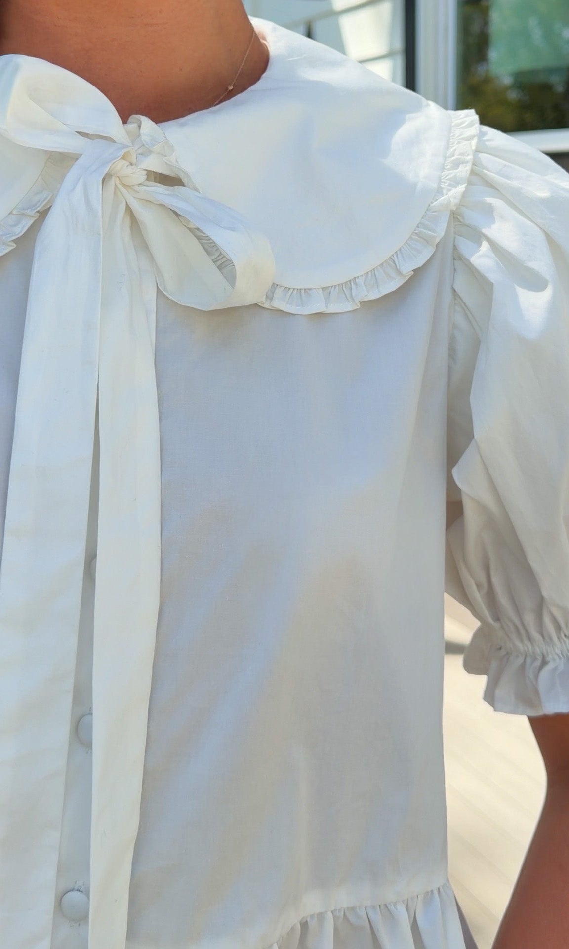 white cotton blouse with peter pan collar, puff sleeves, tie front bow and peplum hem