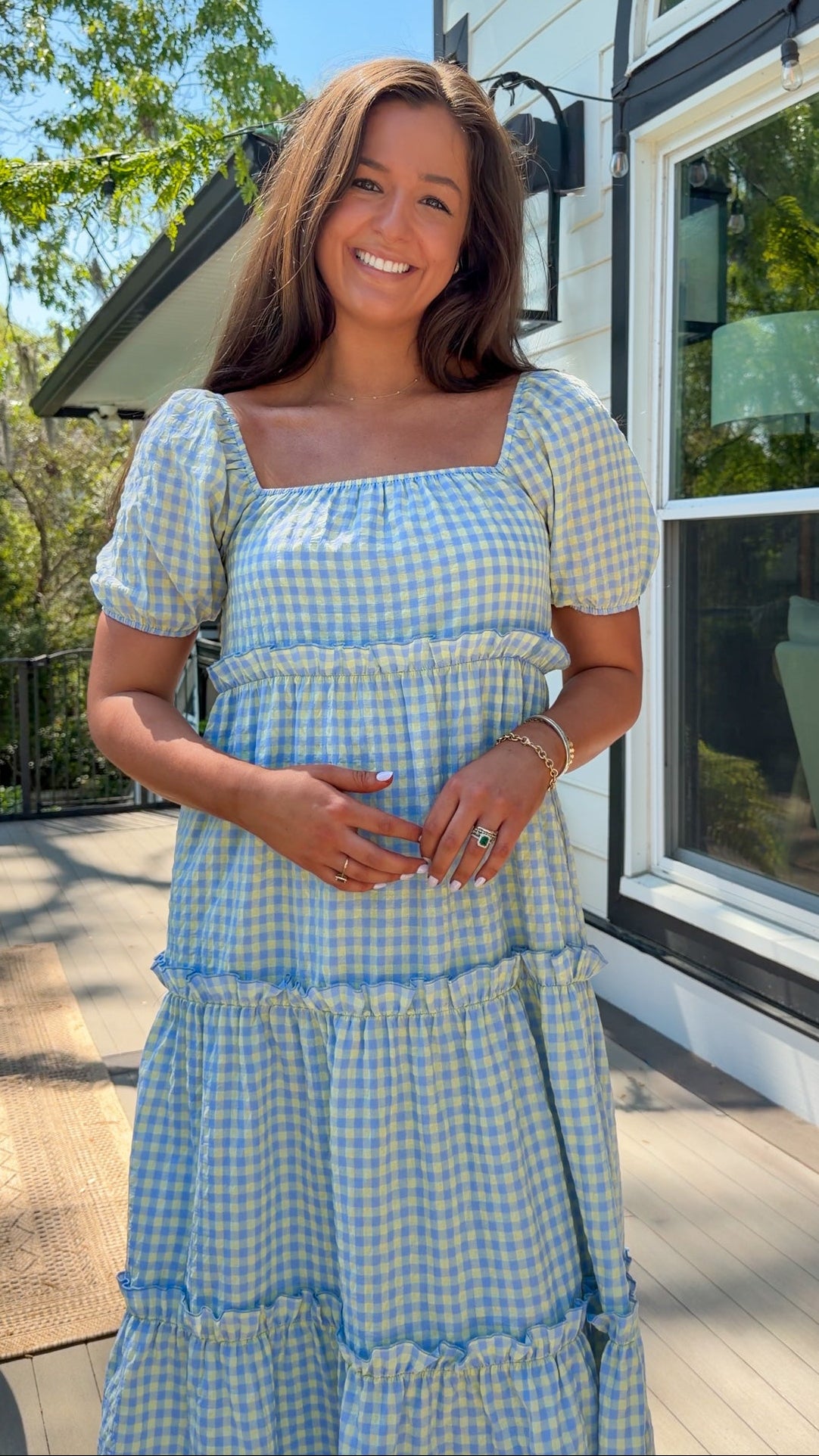 Woman wearing a blue and white checkered dress standing outdoors.