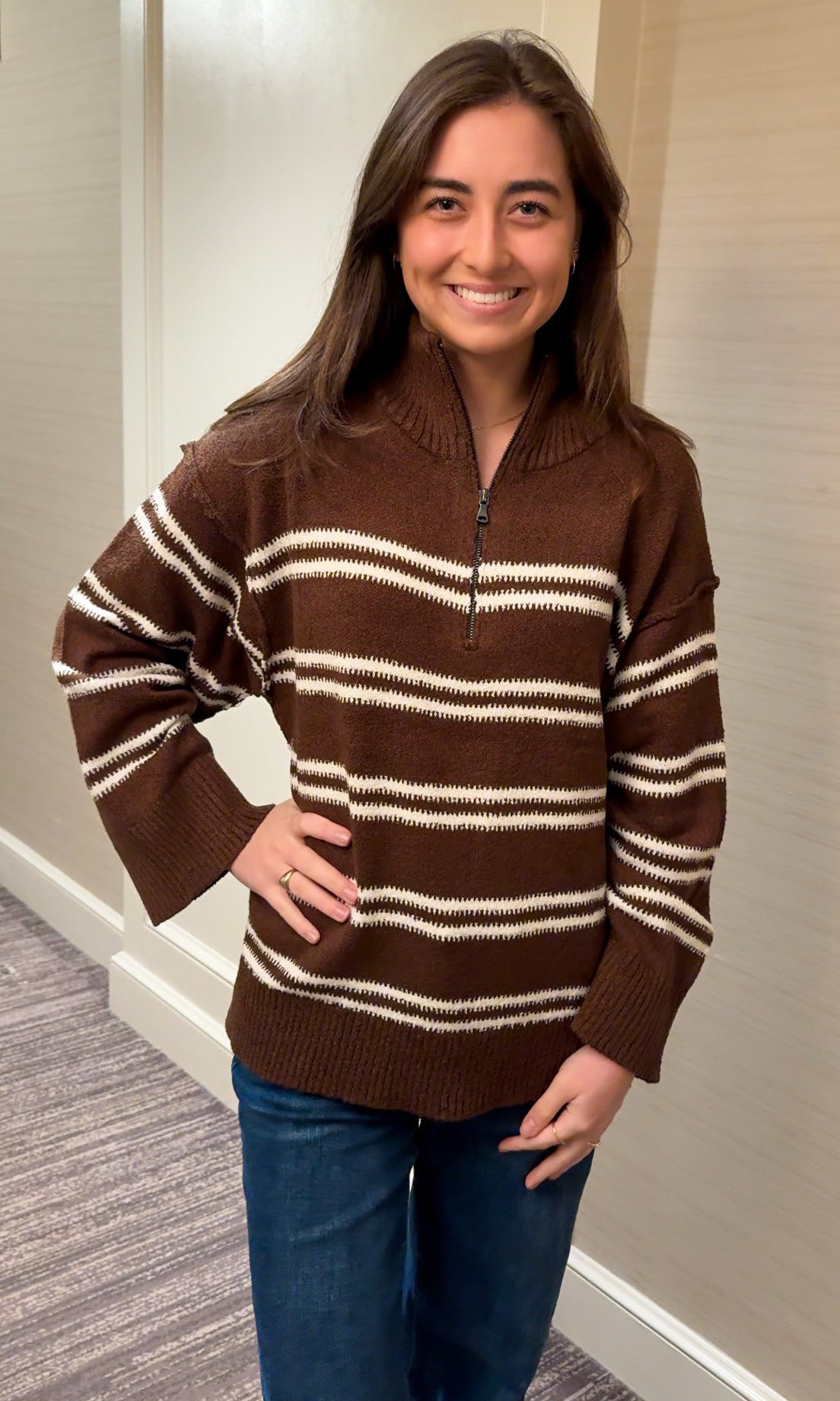 Woman wearing a brown and white striped sweater indoors.