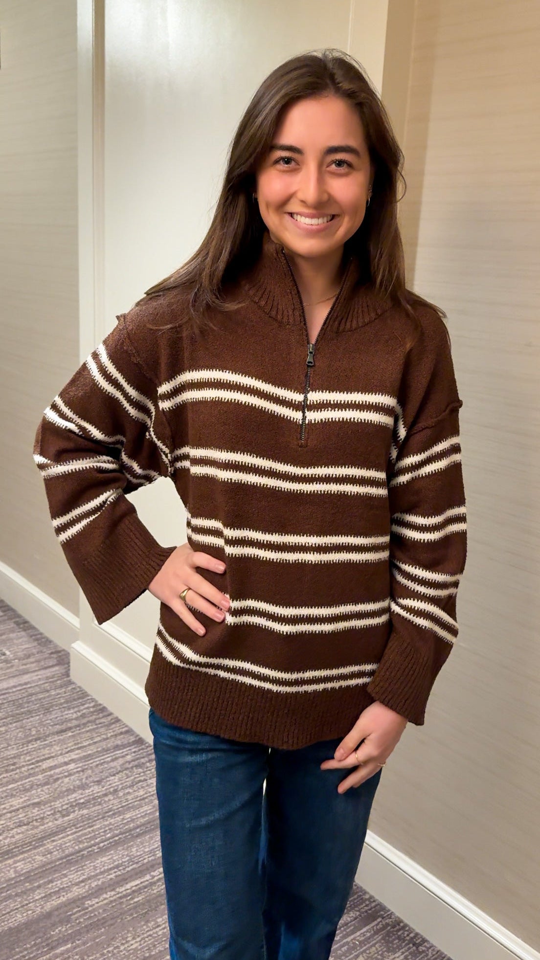 Woman wearing a brown and white striped sweater indoors.