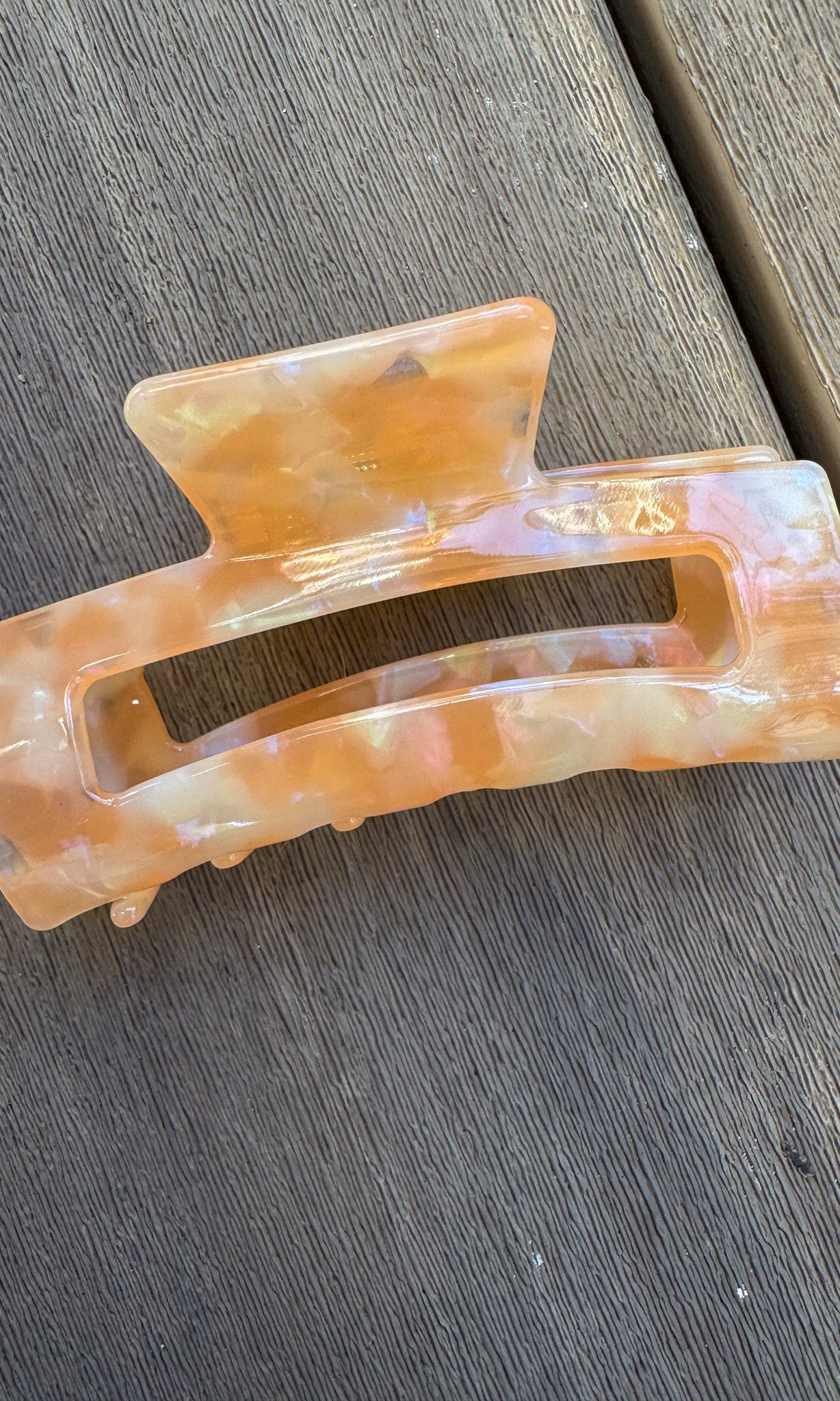 Marbled orange and beige hair clip on a wooden surface