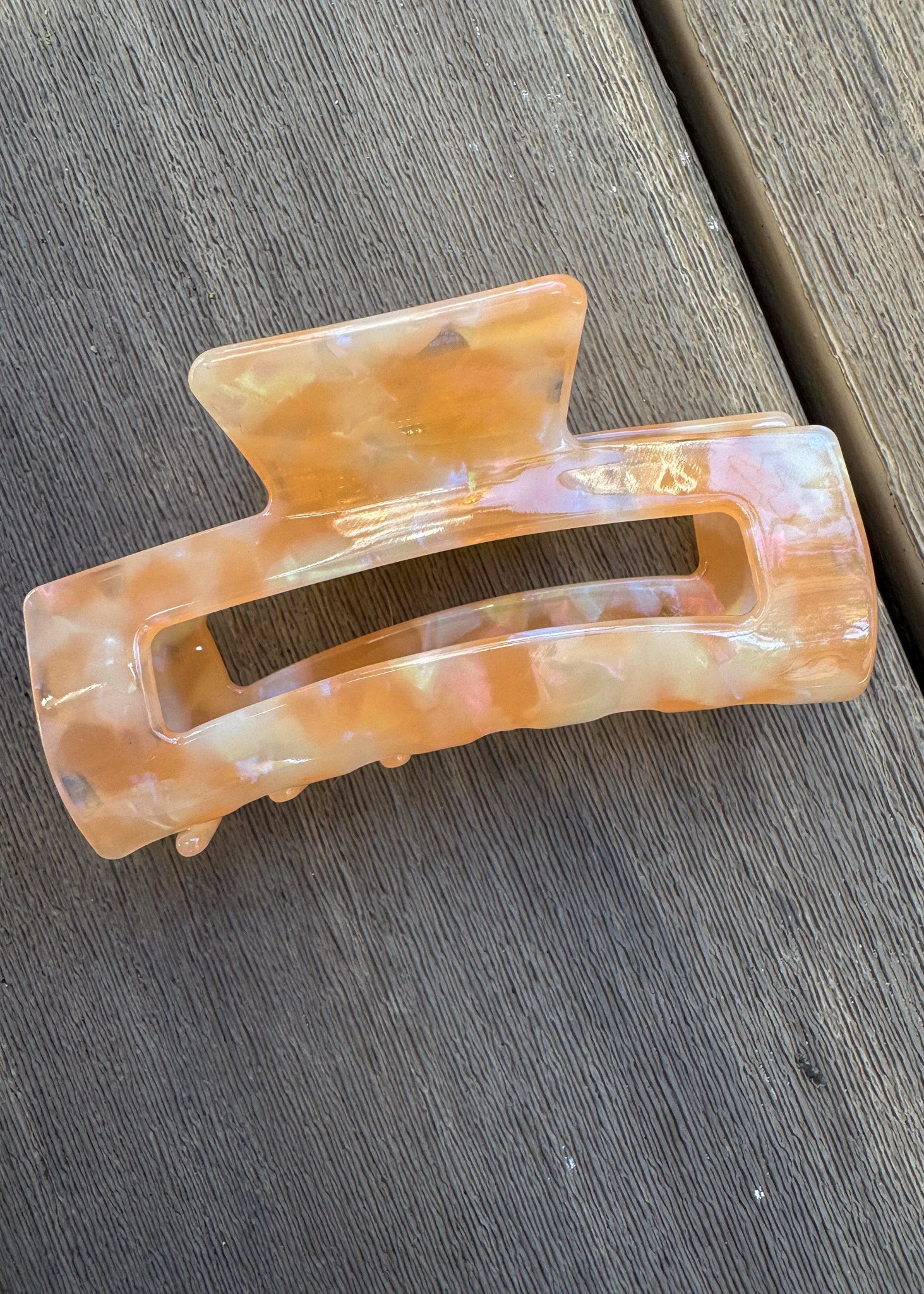 Marbled orange and beige hair clip on a wooden surface