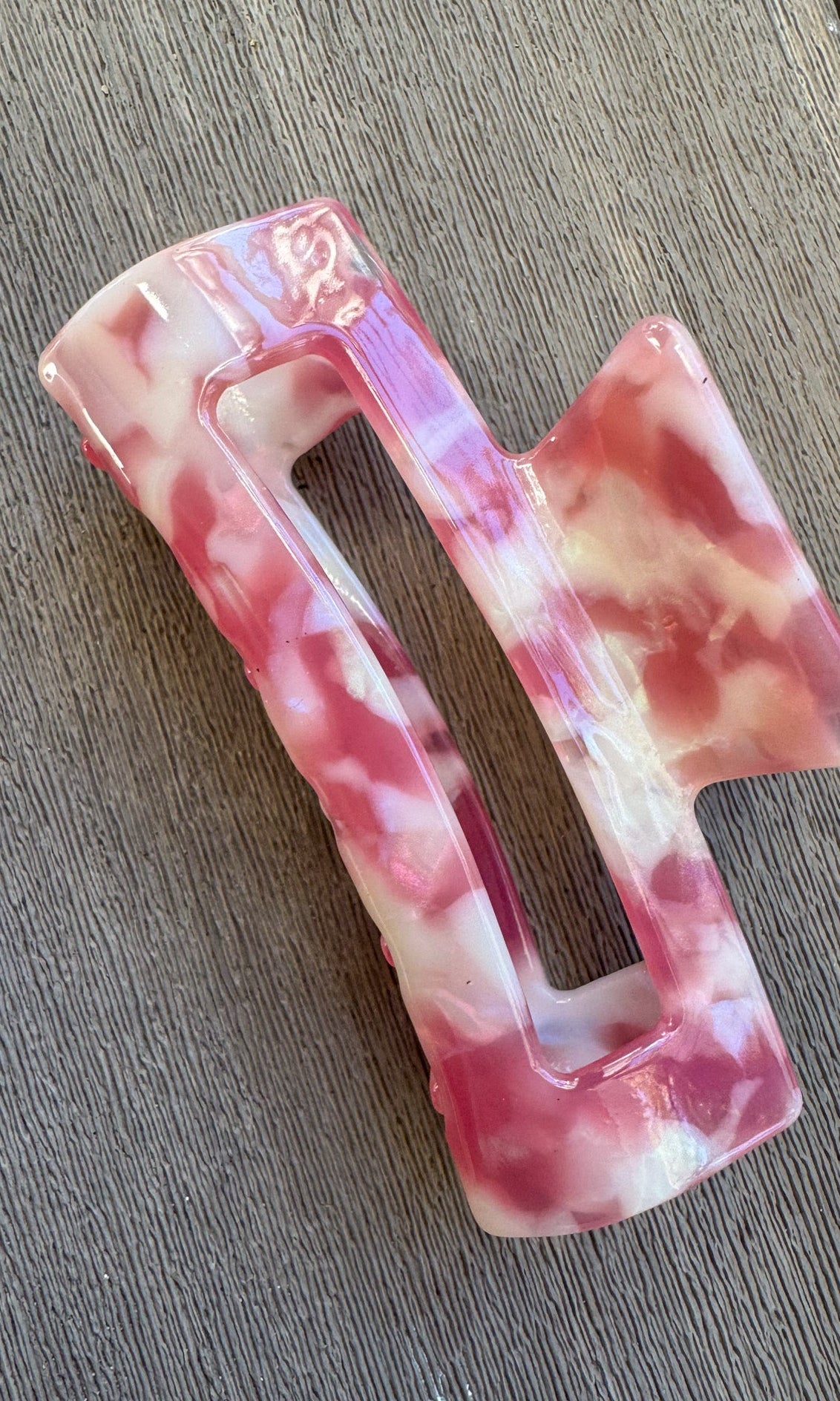 Pink and white marbled hair clip on a wooden surface
