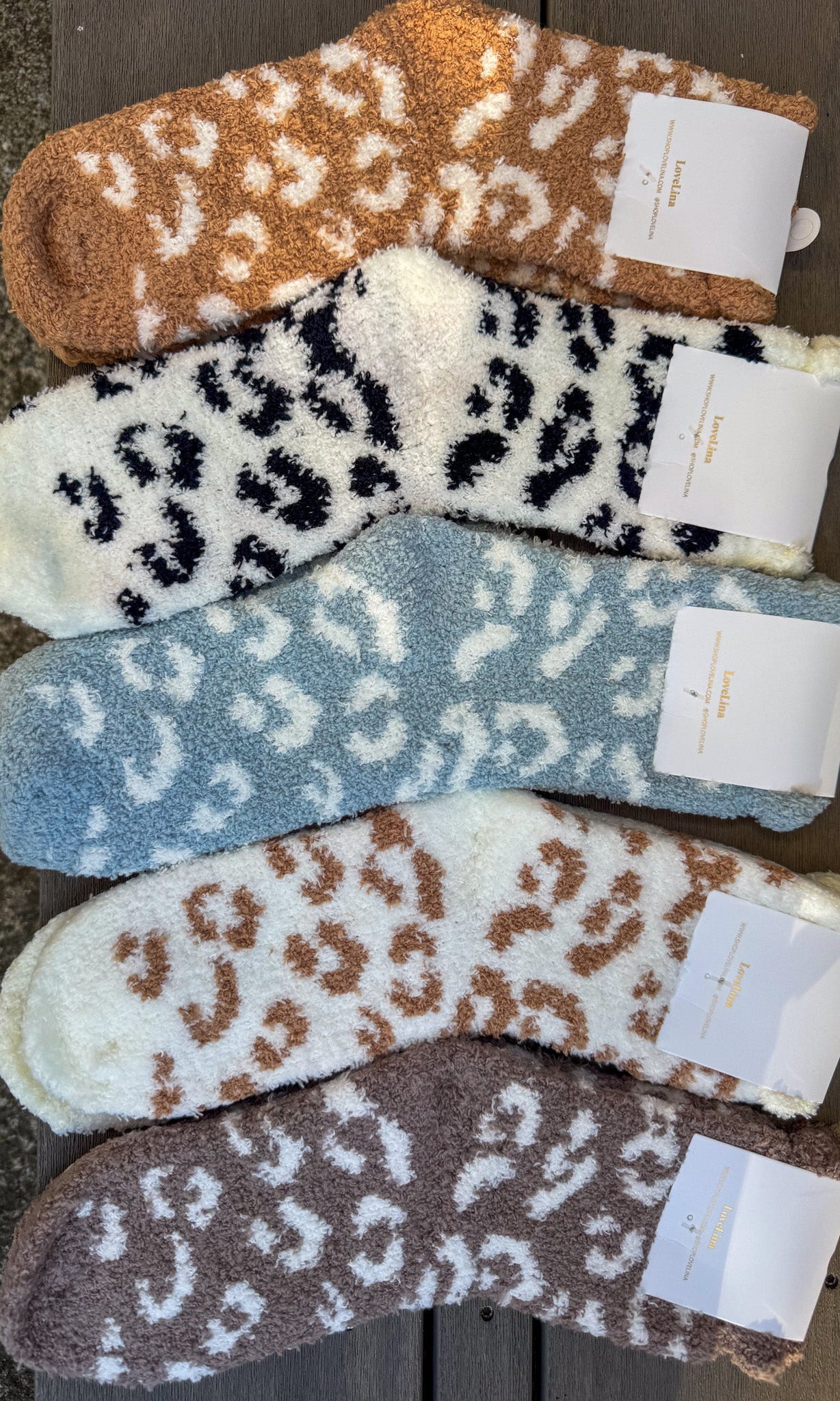Five pairs of leopard print socks in different colors on a wooden surface.