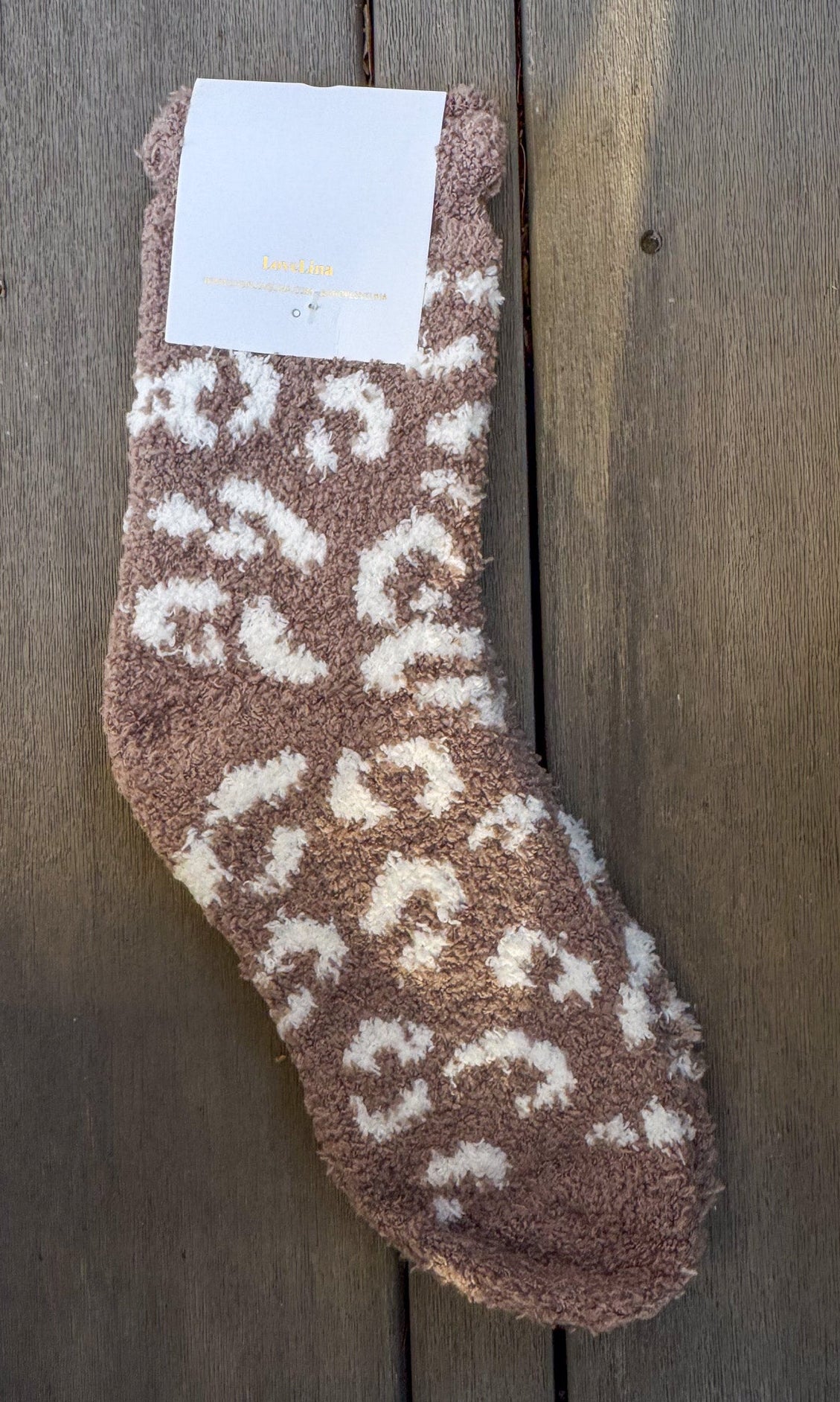 Brown fuzzy sock with white patterns on a wooden surface