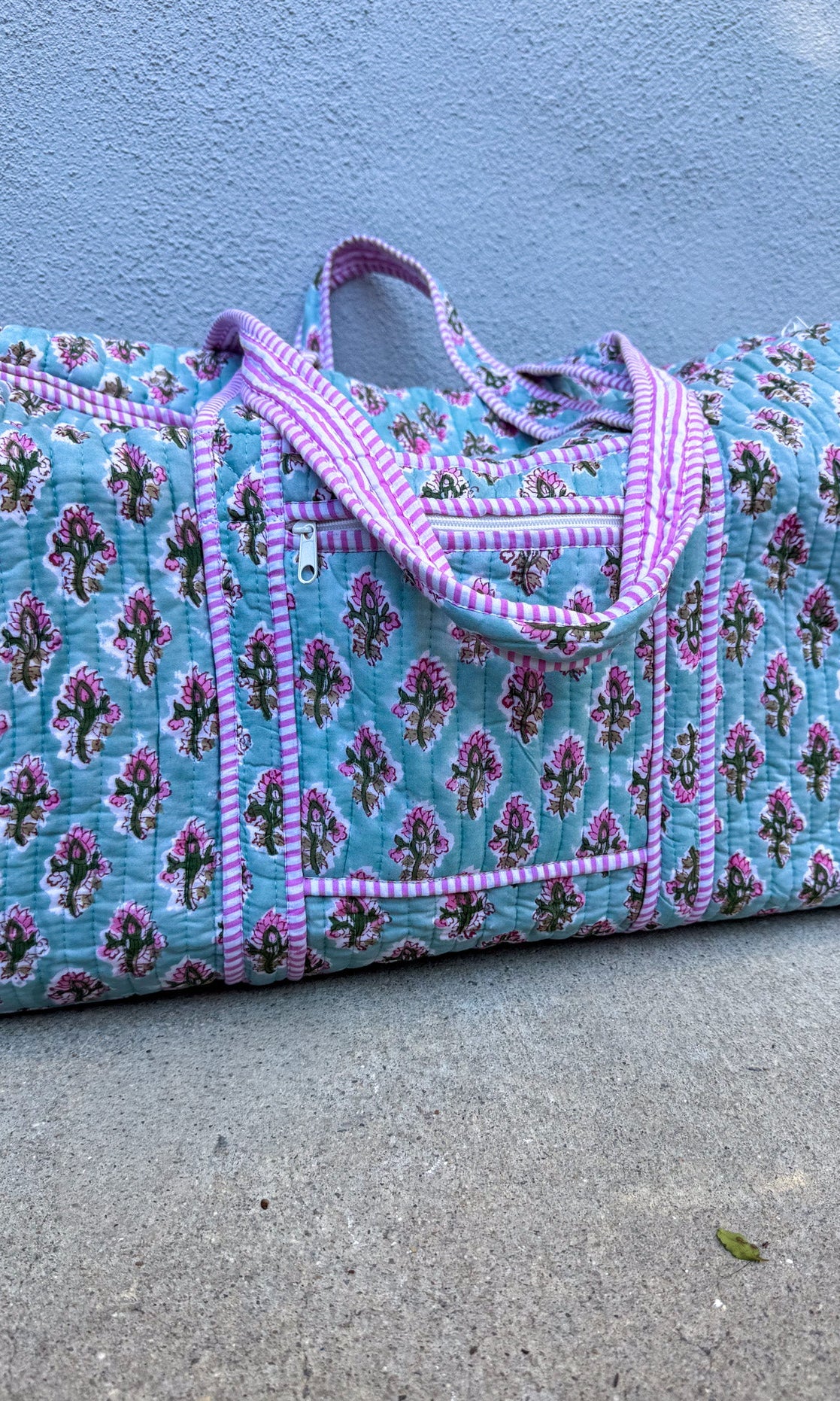 Floral patterned bag with pink trim on a concrete surface