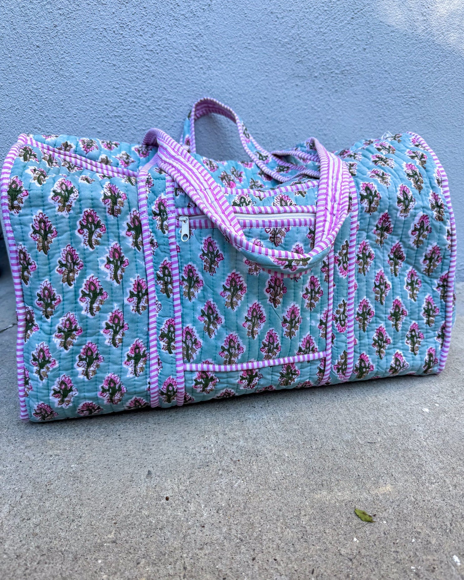 Floral patterned bag with pink trim on a concrete surface
