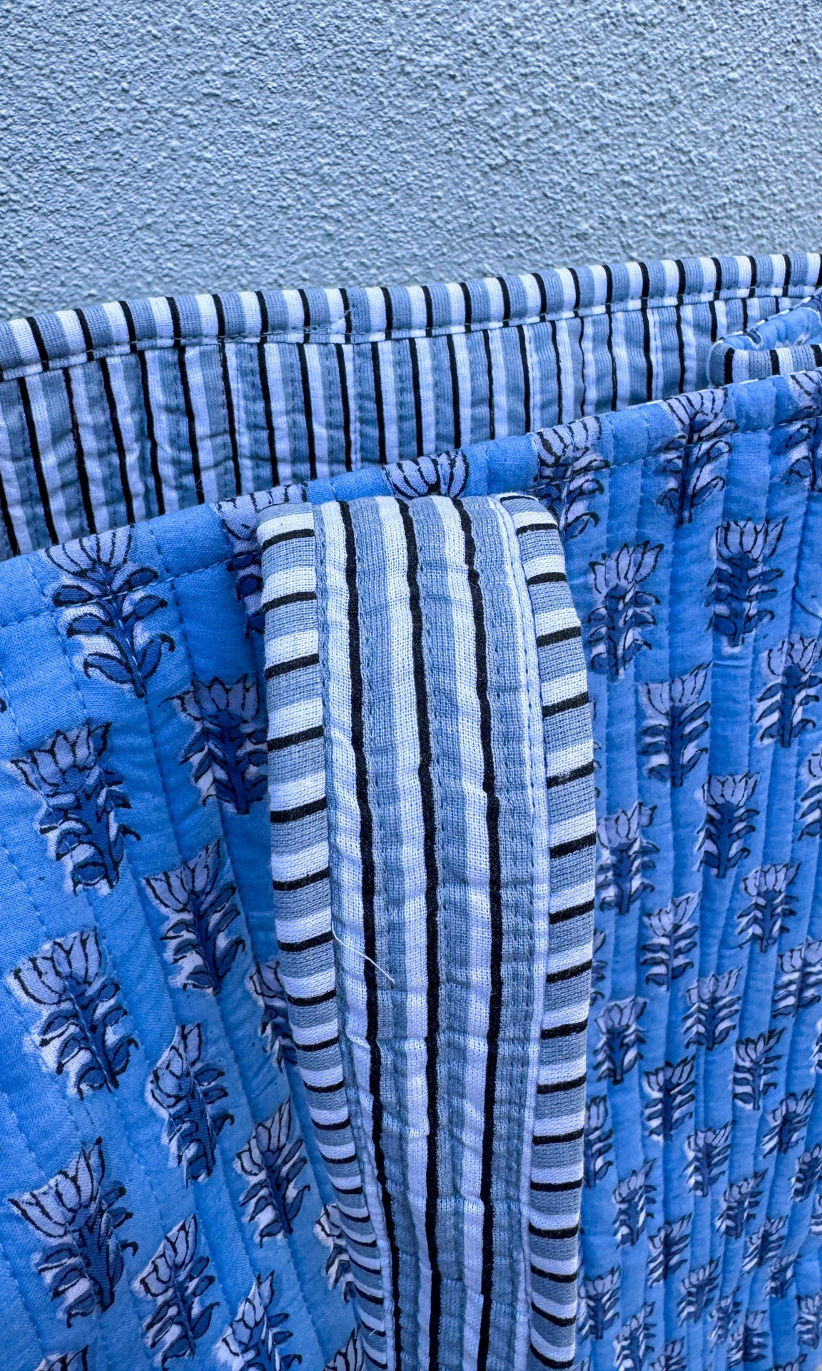Stack of blue patterned fabrics against a light blue background
