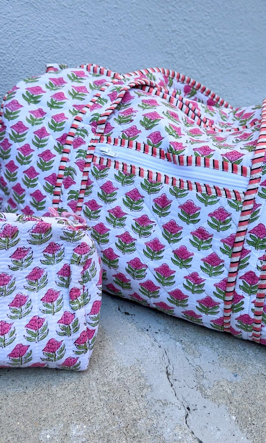 Two fabric bags with pink floral pattern on a concrete surface.