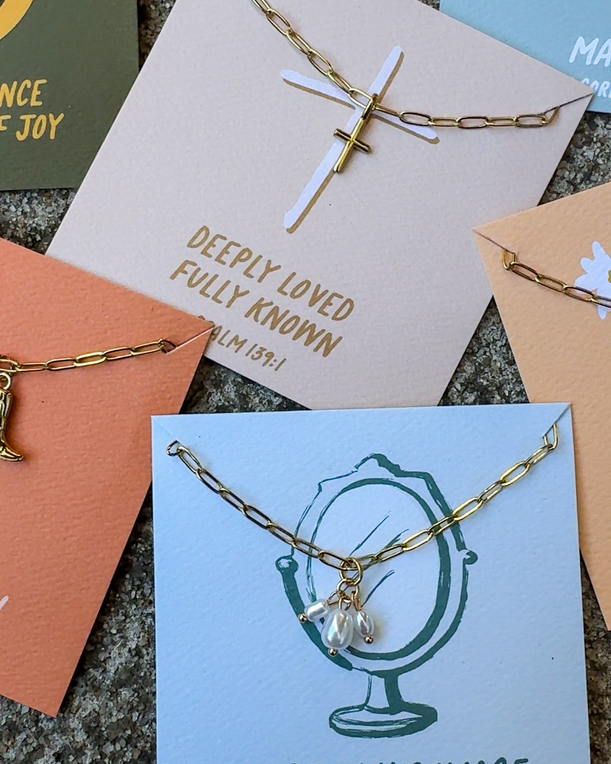 Gold necklace with a cross pendant on a card with text and other cards in the background.