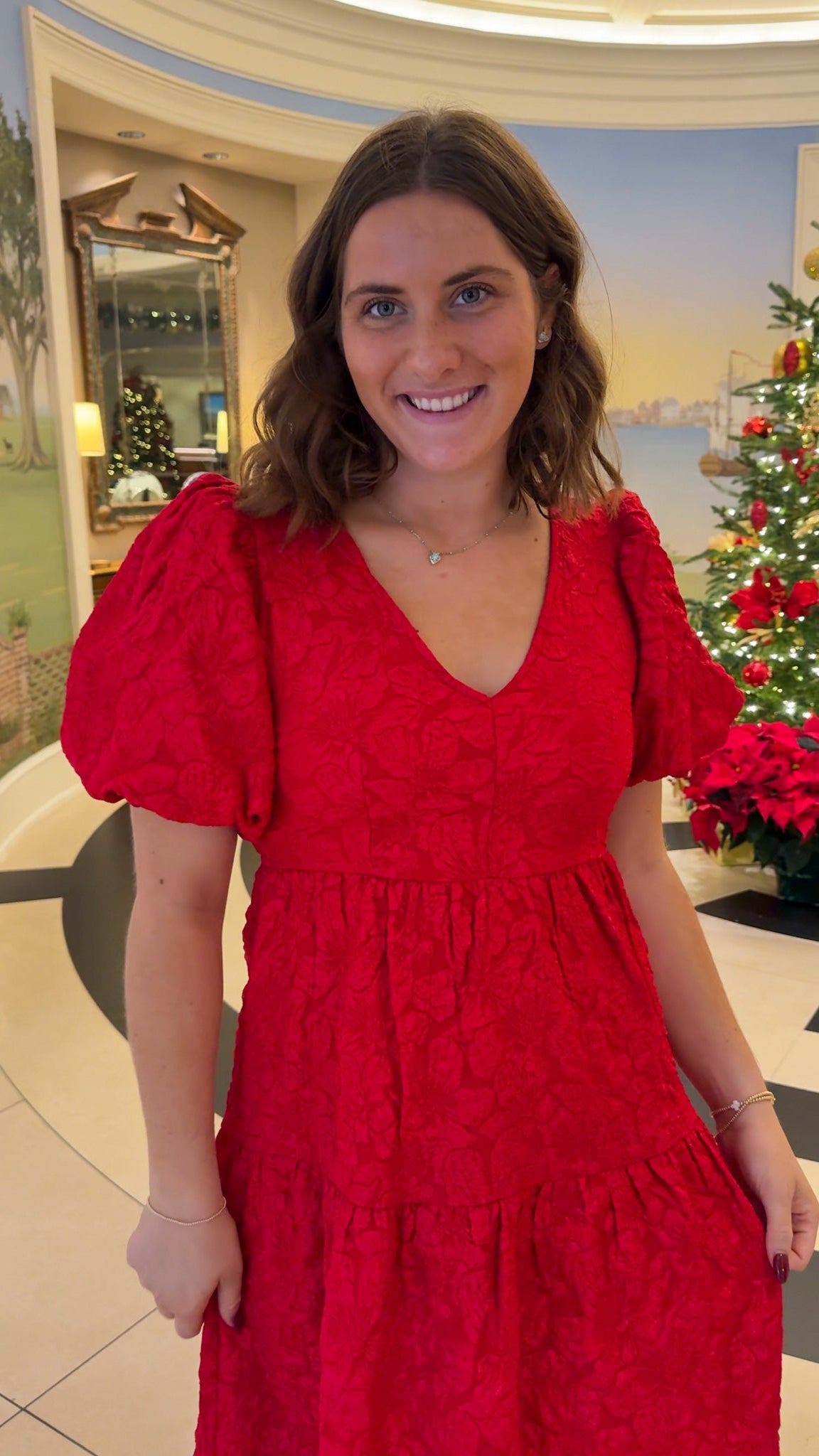 red jacquard maxi dress with puff sleeves and tiered skirt bottom and open back tie bow v neck holiday christmas dress closeup