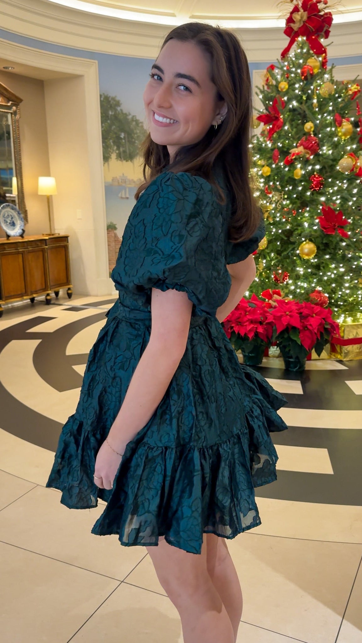 Hunter green floral textured mini dress with puff sleeves, covered button details, tie waist, and tiered skirt.