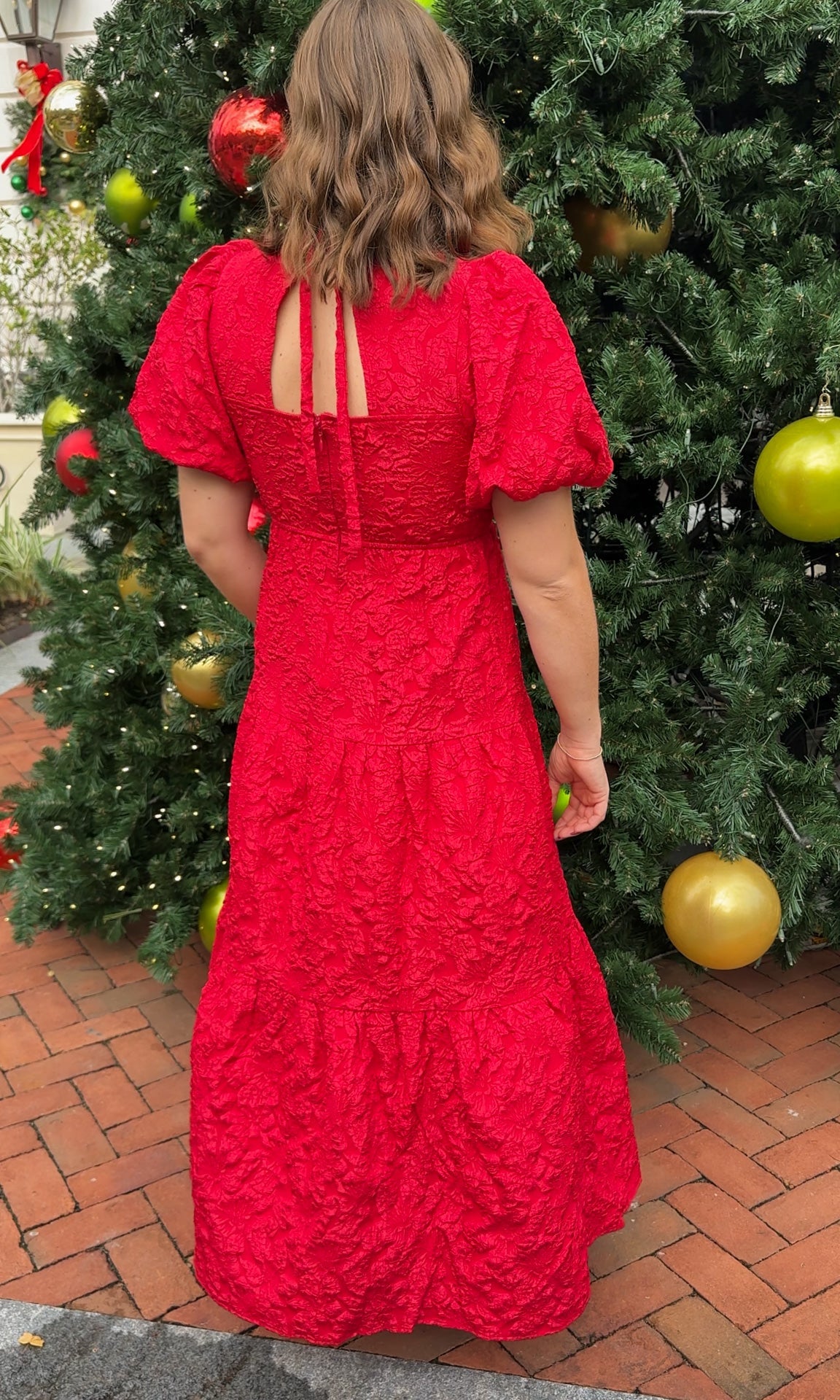 red jacquard maxi dress with puff sleeves and tiered skirt bottom and open back tie bow v neck holiday christmas dress