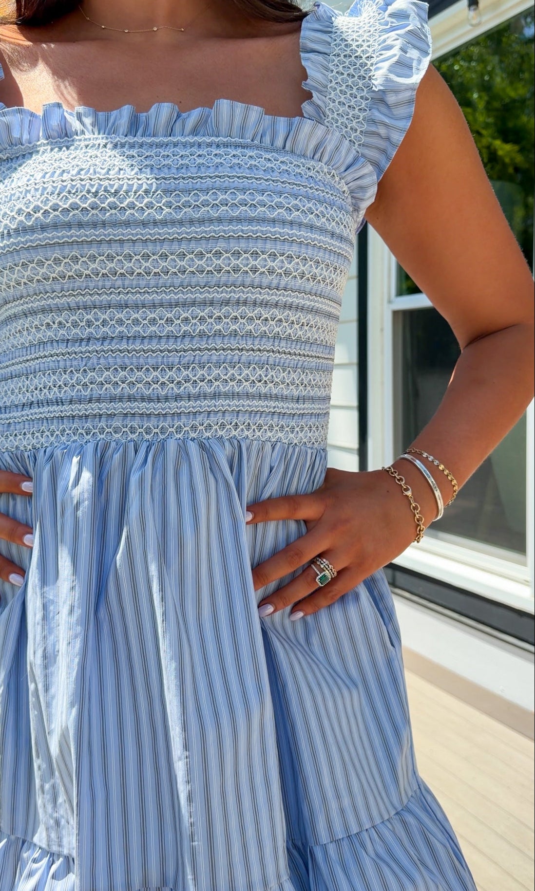 Woman wearing a blue and white striped dress with ruffled sleeves.