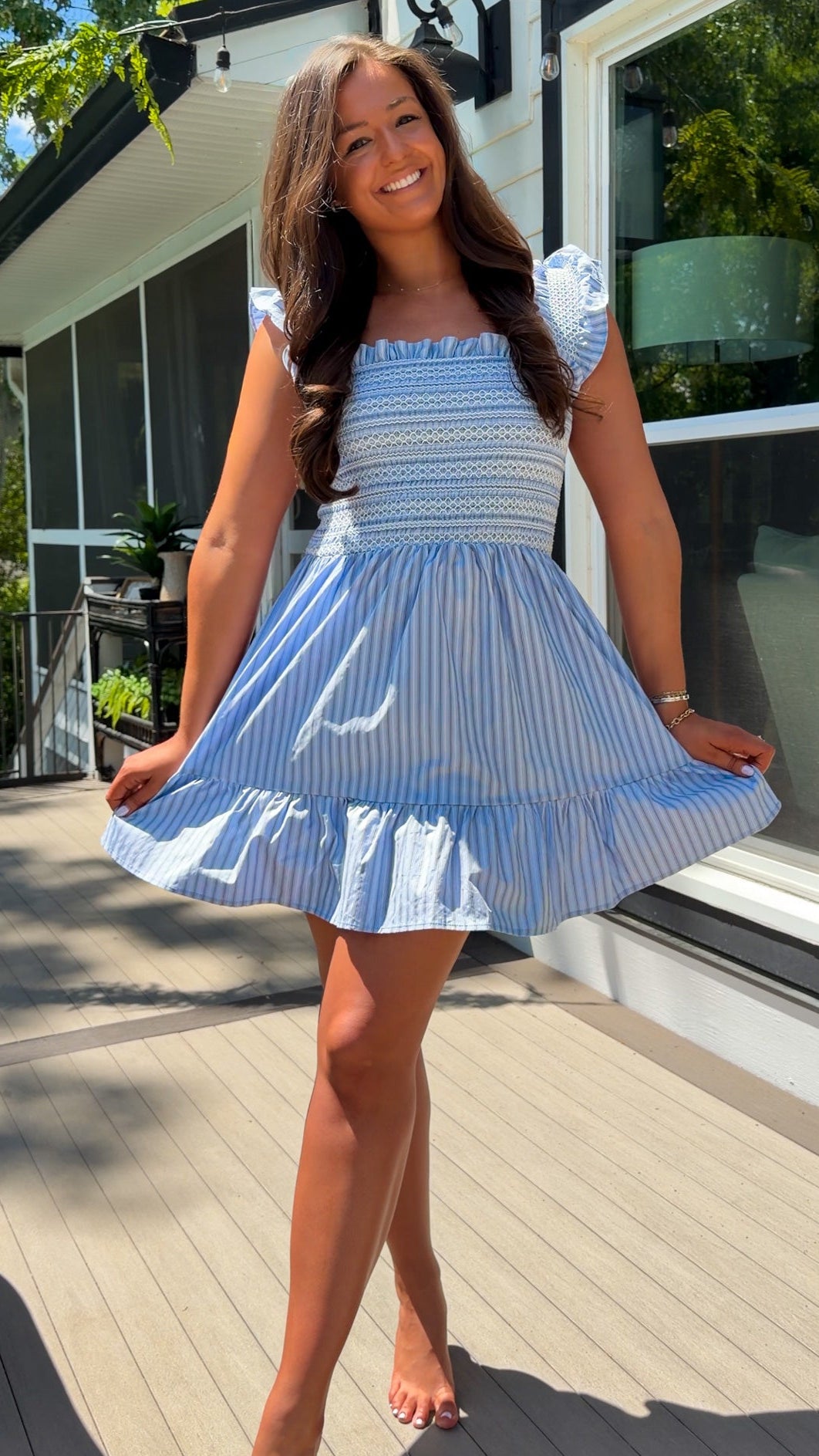 Woman in a blue and white striped dress standing on a wooden deck.