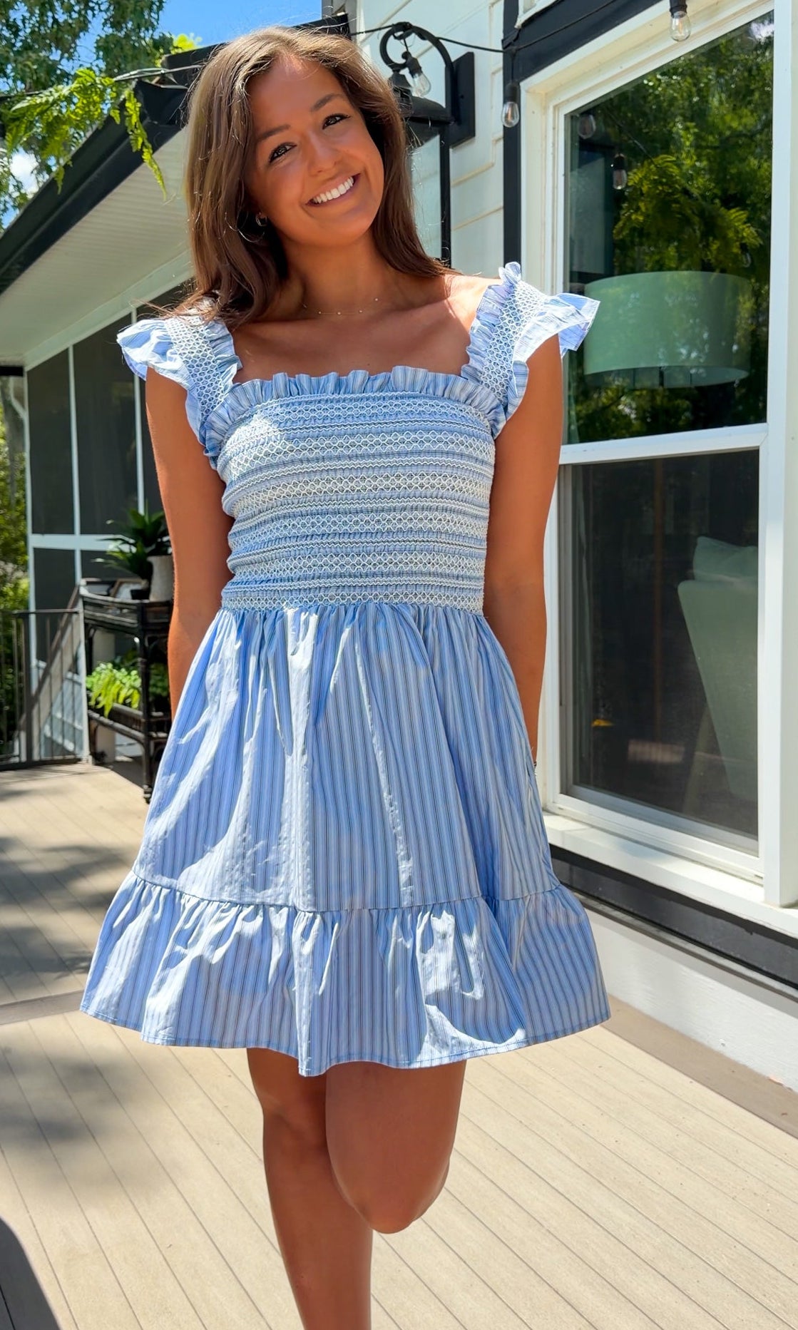Woman wearing a blue and white striped dress standing outdoors.