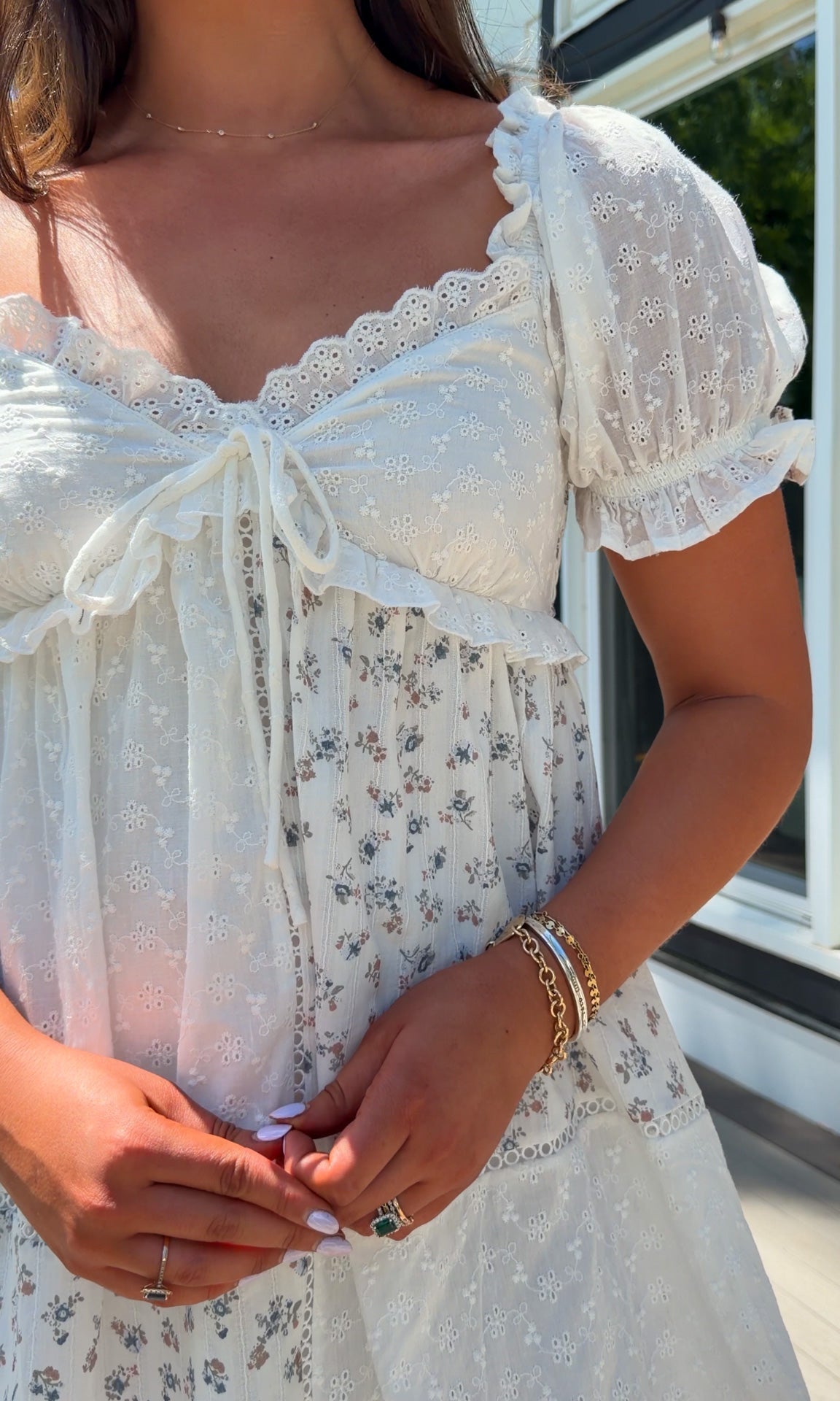 cream floral mini dress with eyelet lace, puff sleeves, scalloped neckline, and front tie detail