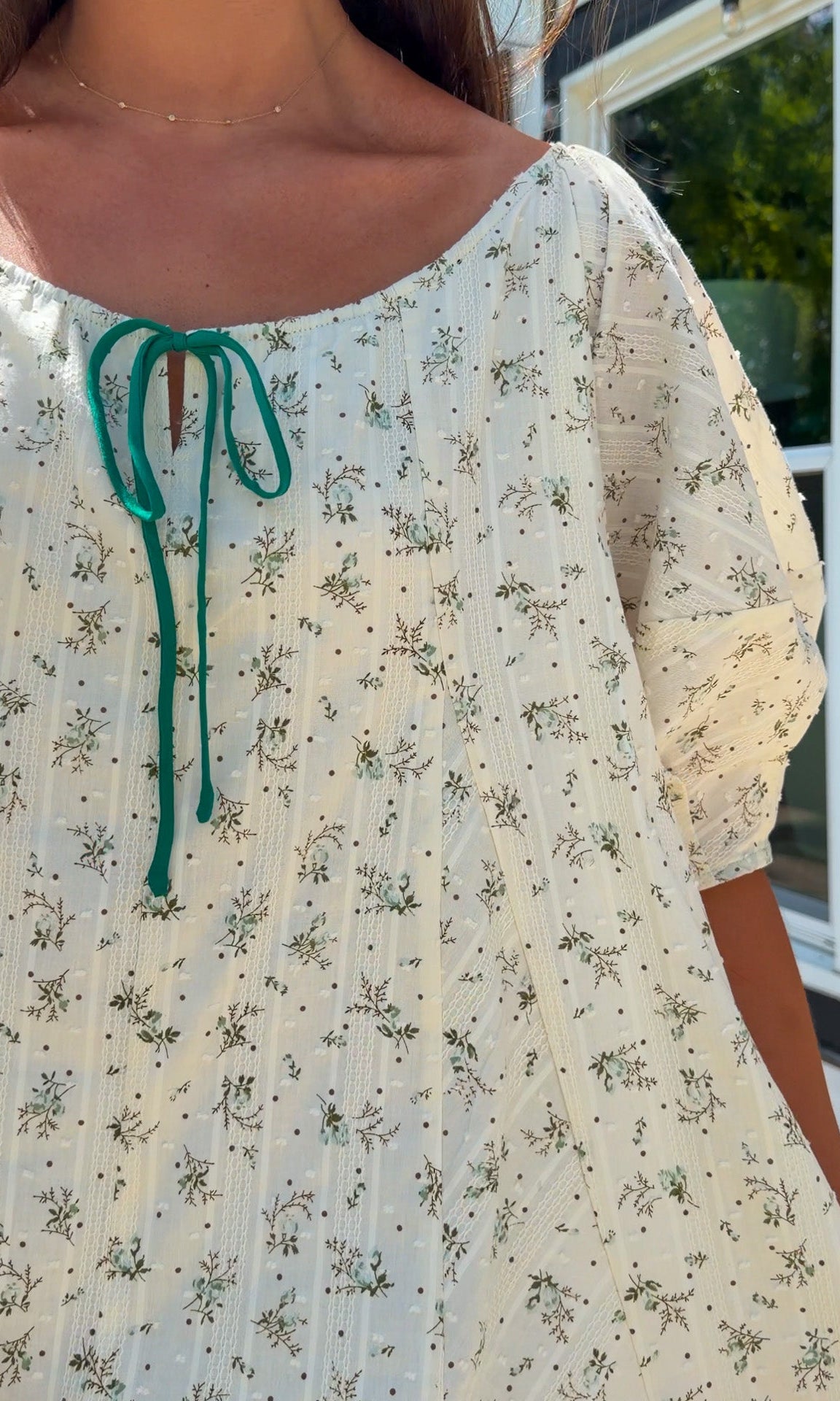 cream floral romper with puff sleeves and green tie neckline, flowy fit with built-in shorts