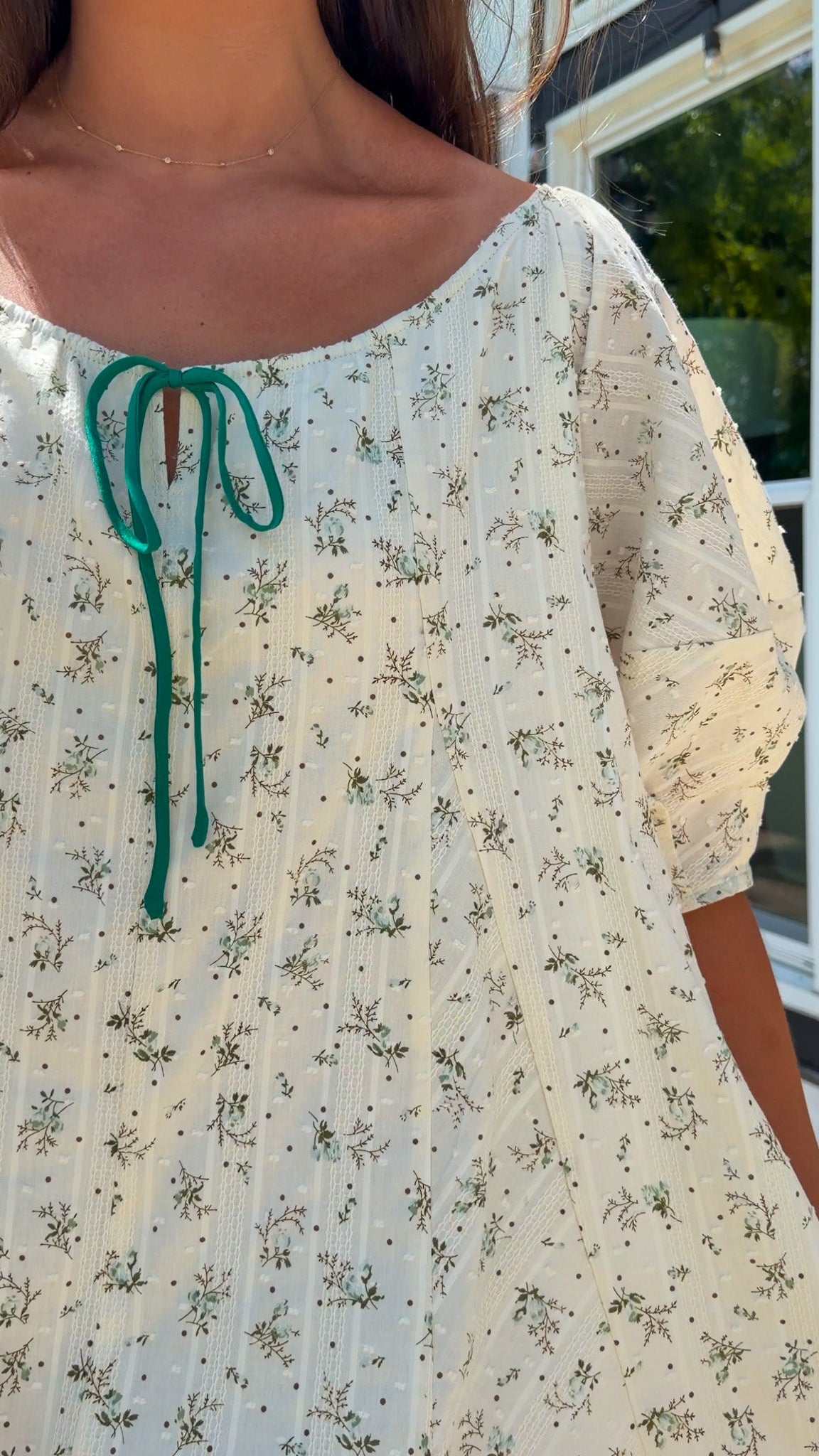 cream floral romper with puff sleeves and green tie neckline, flowy fit with built-in shorts