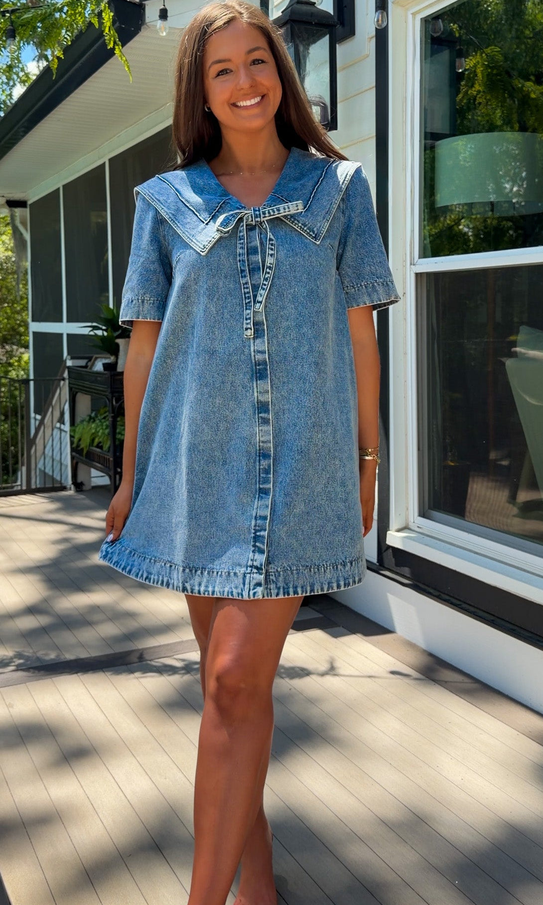 light wash denim mini dress with oversized collar, tie front detail, short sleeves, and slightly oversized fit
