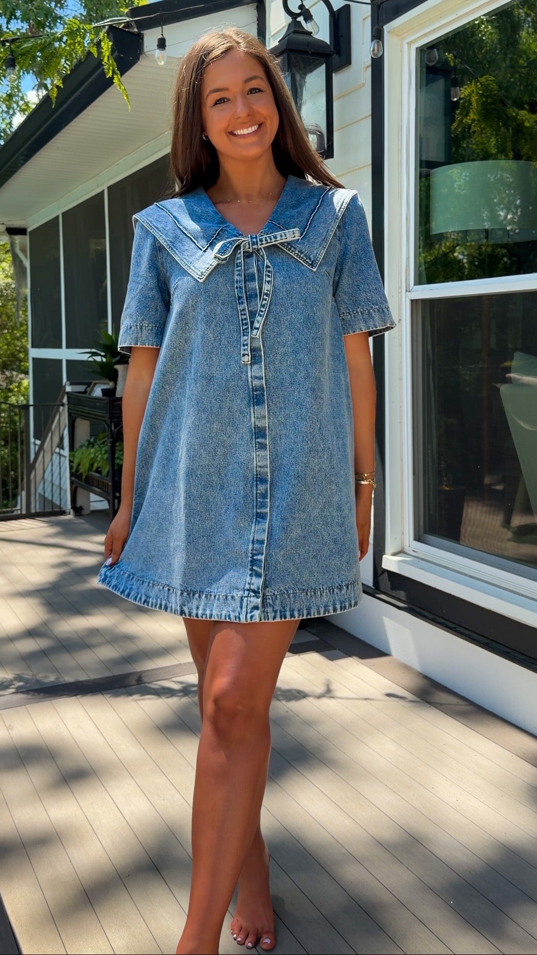light wash denim mini dress with oversized collar, tie front detail, short sleeves, and slightly oversized fit
