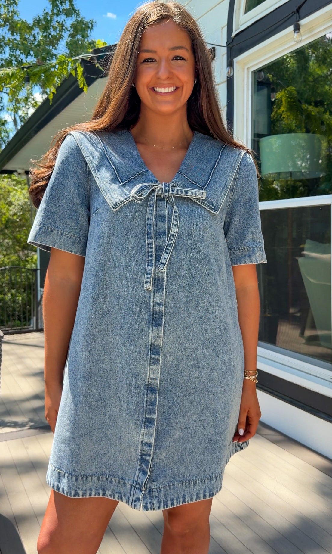 light wash denim mini dress with oversized collar, tie front detail, short sleeves, and slightly oversized fit