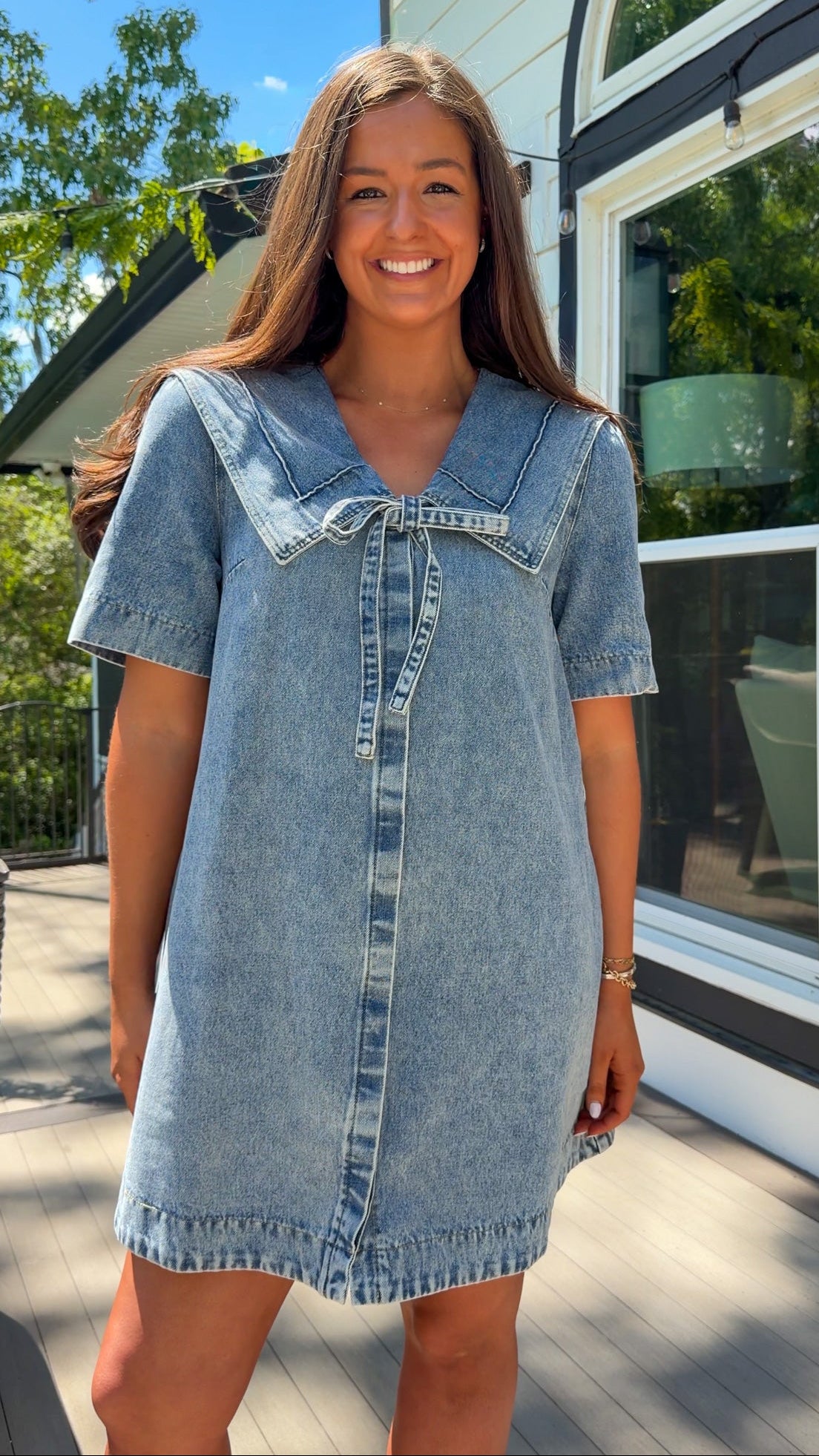light wash denim mini dress with oversized collar, tie front detail, short sleeves, and slightly oversized fit