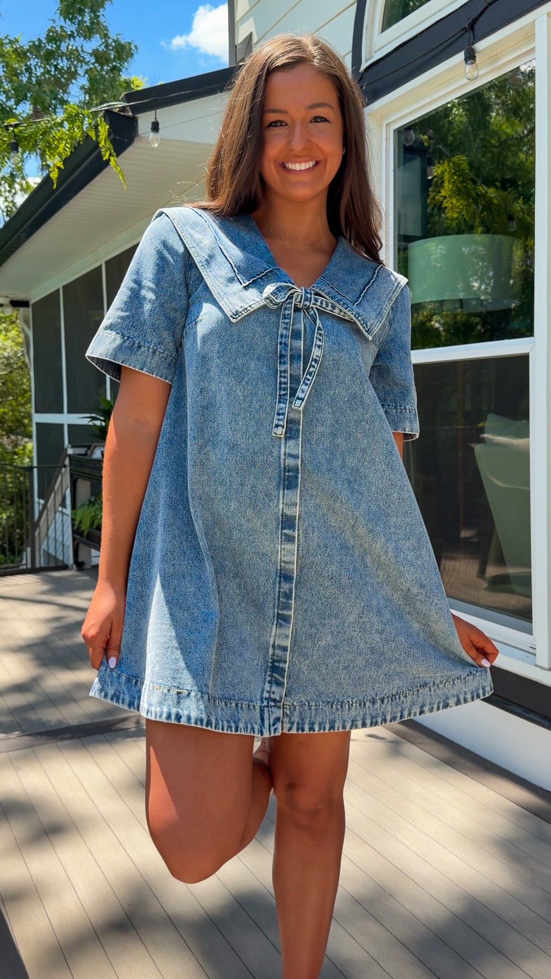 light wash denim mini dress with oversized collar, tie front detail, short sleeves, and slightly oversized fit