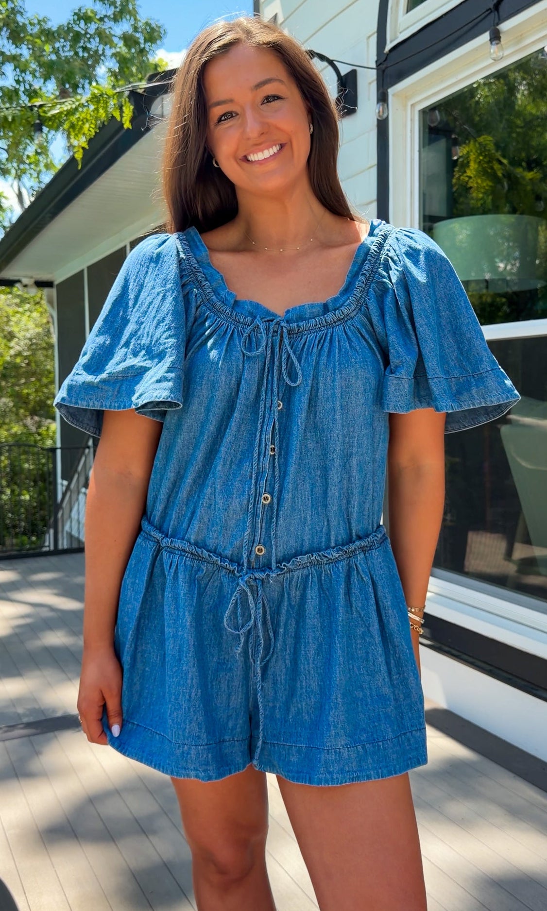 Denim romper with butterfly sleeves, tie neckline, and drawstring waist in blue