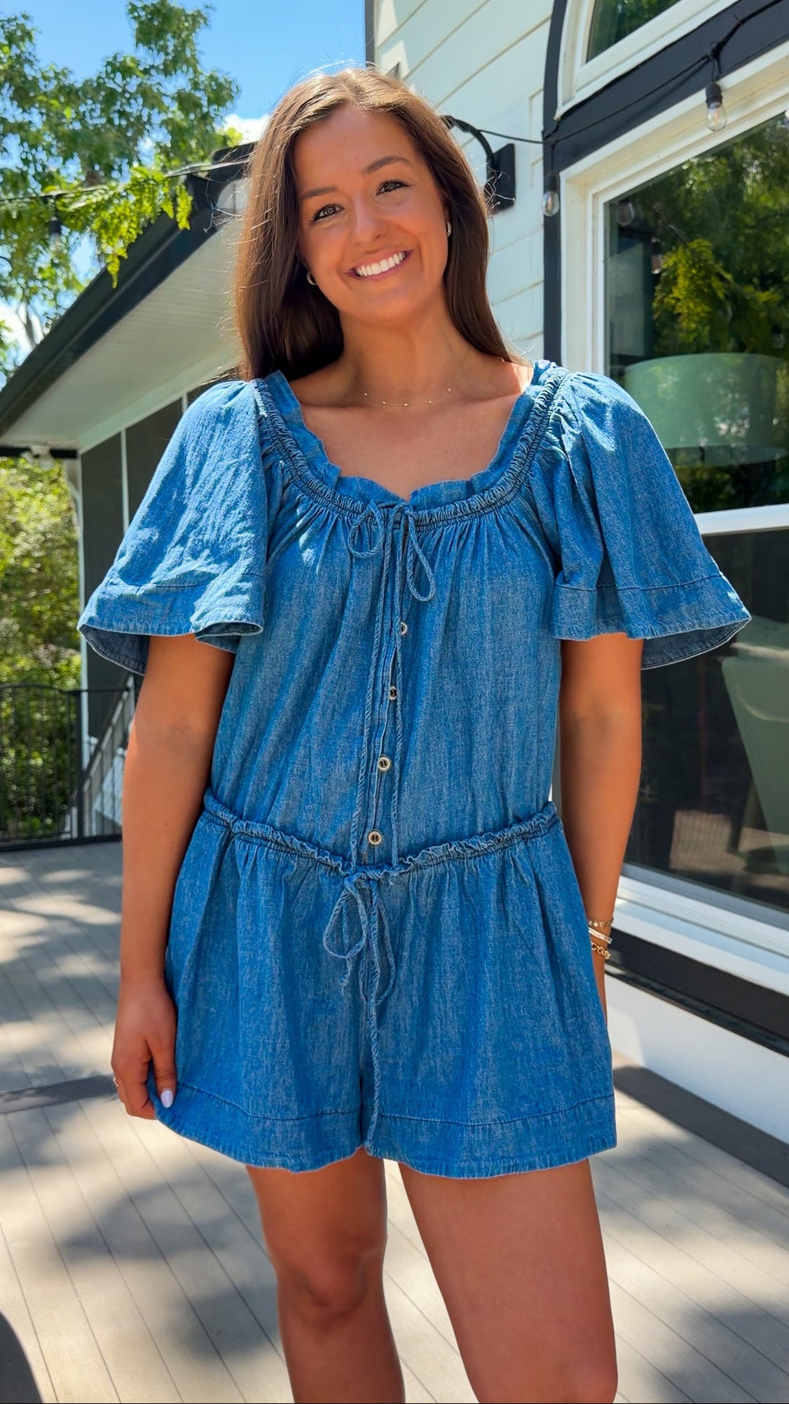 Denim romper with butterfly sleeves, tie neckline, and drawstring waist in blue