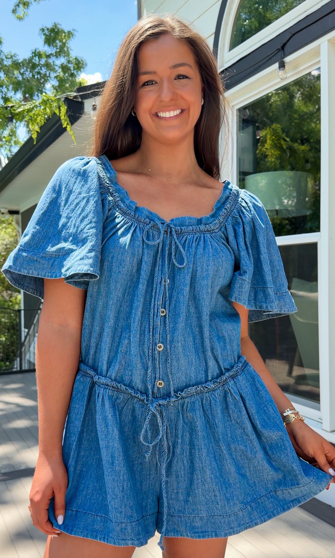 Denim romper with butterfly sleeves, tie neckline, and drawstring waist in blue