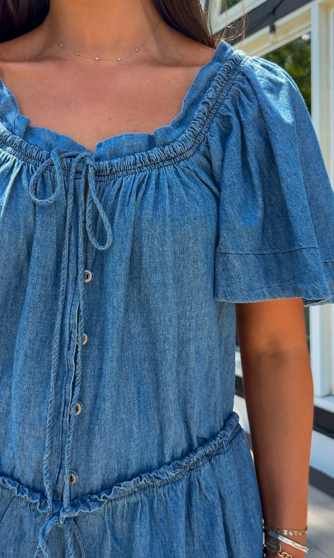 Denim romper with butterfly sleeves, tie neckline, and drawstring waist in blue