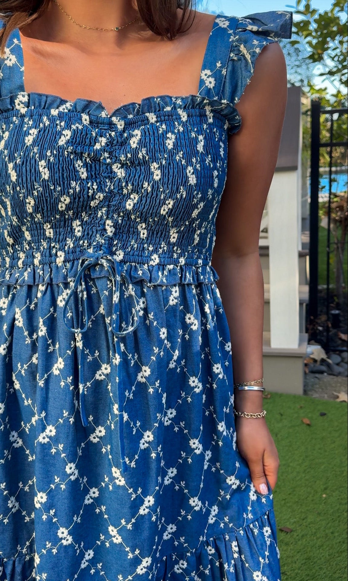 Denim blue and off-white floral tiered maxi dress with smocked bodice and flutter straps.