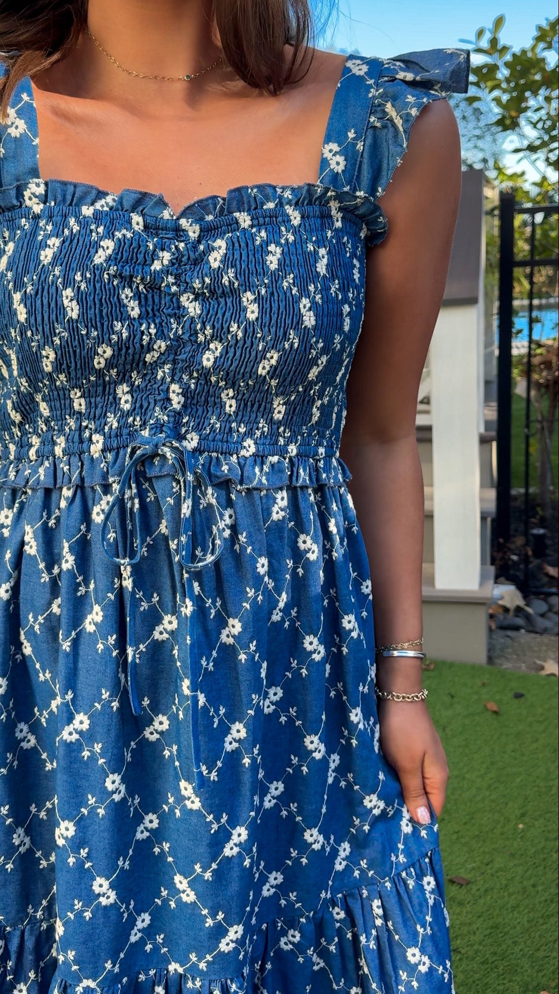Denim blue and off-white floral tiered maxi dress with smocked bodice and flutter straps.