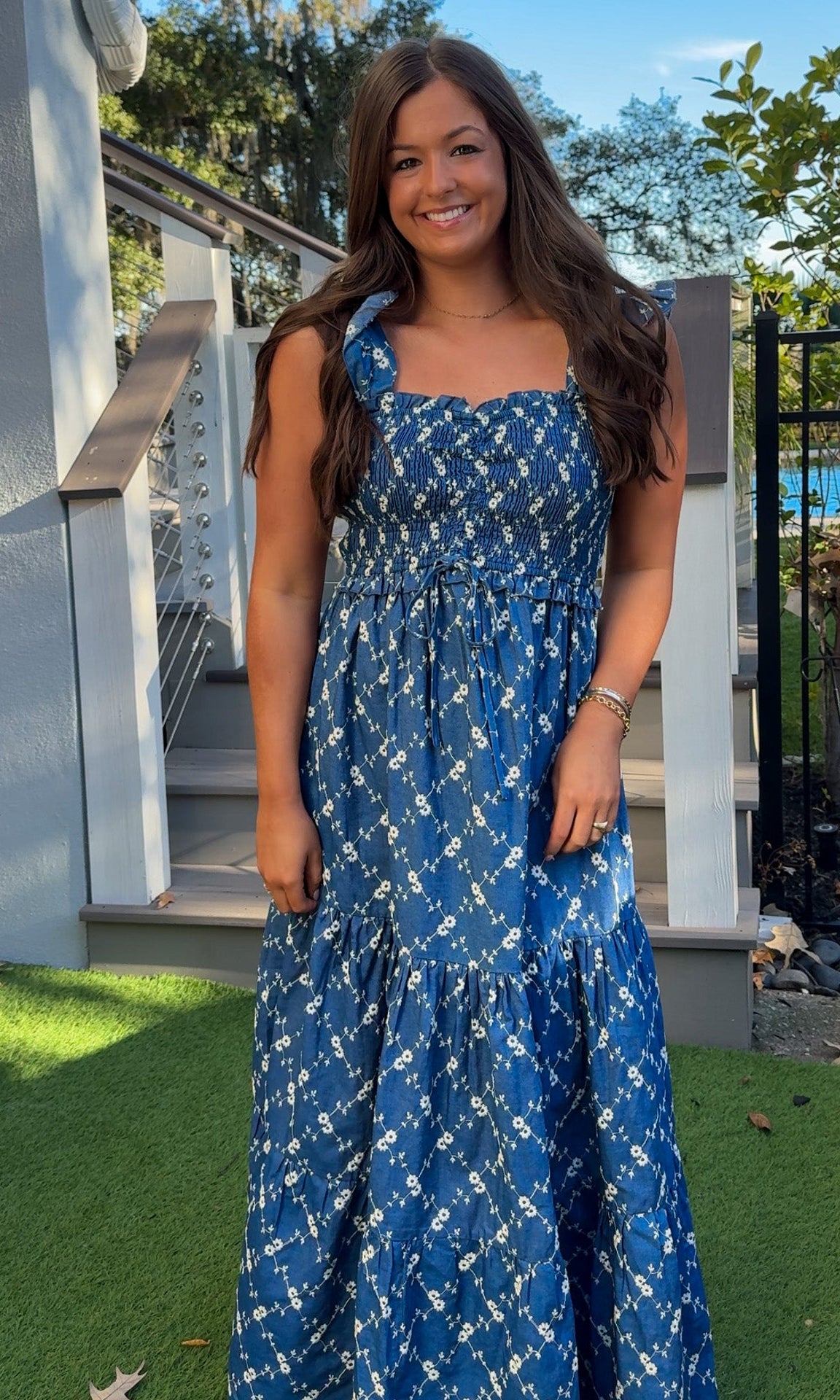 Denim blue and off-white floral tiered maxi dress with smocked bodice and flutter straps.
