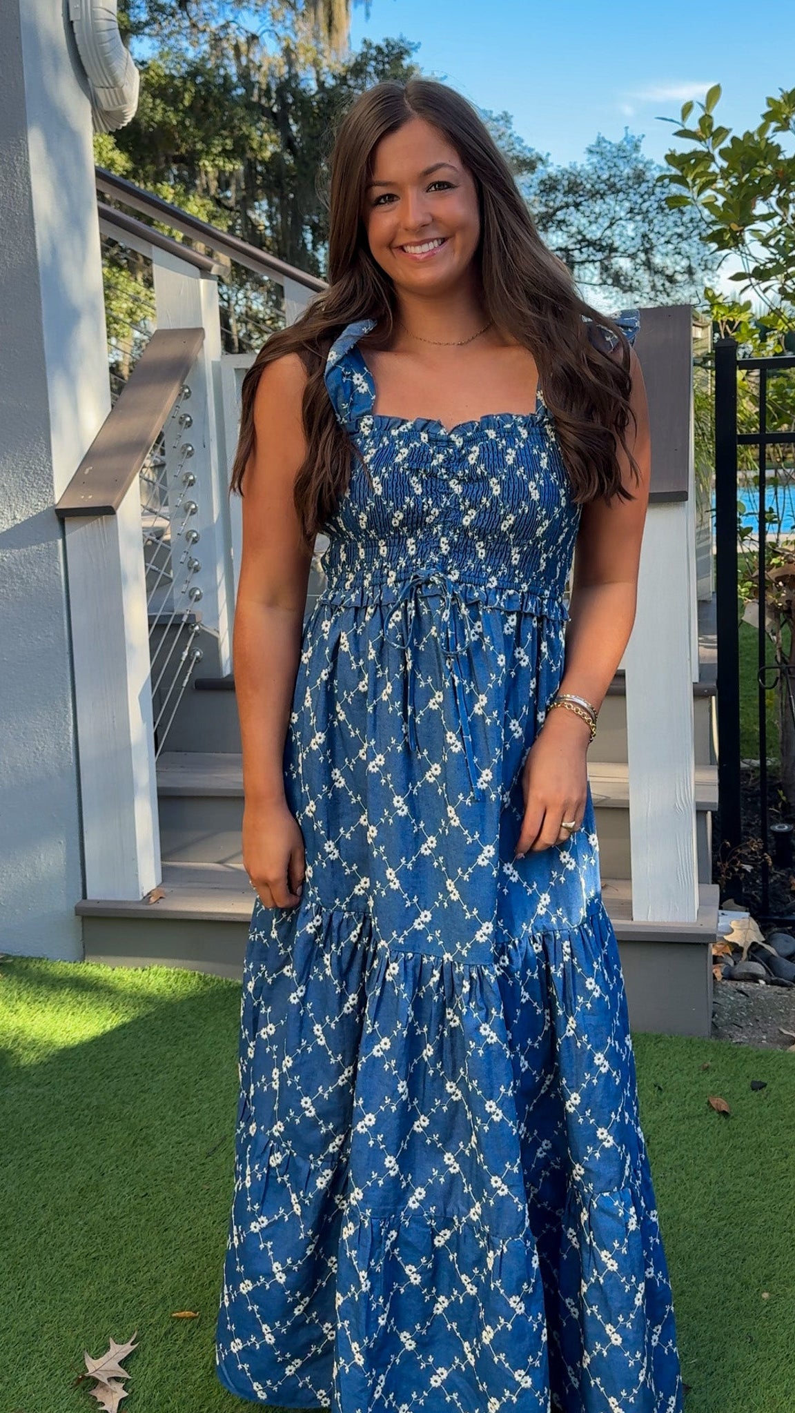 Denim blue and off-white floral tiered maxi dress with smocked bodice and flutter straps.