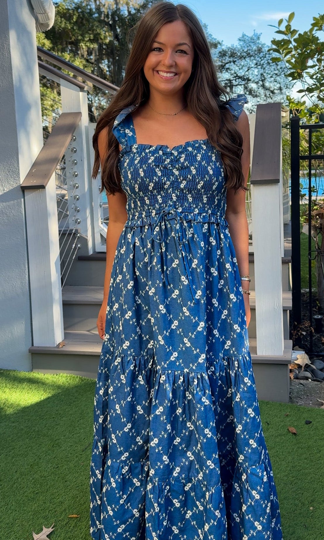 Denim blue and off-white floral tiered maxi dress with smocked bodice and flutter straps.