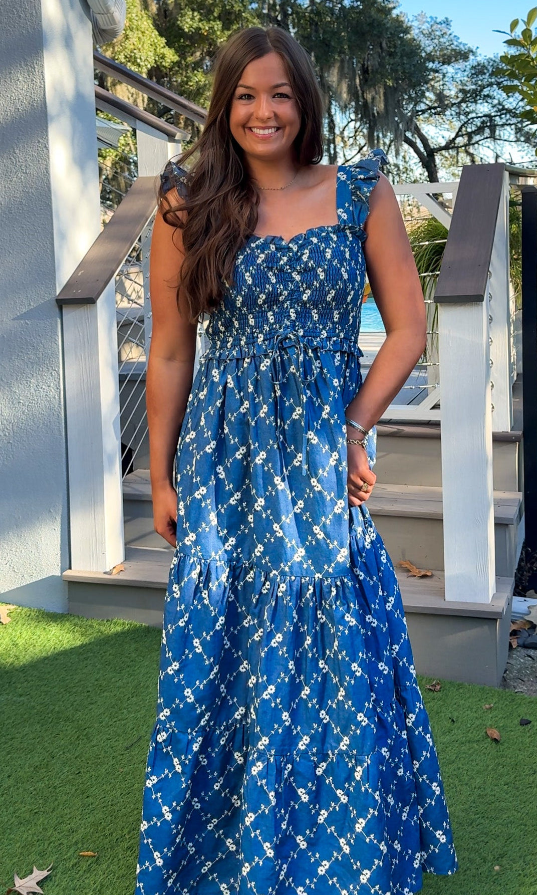 Denim blue and off-white floral tiered maxi dress with smocked bodice and flutter straps.