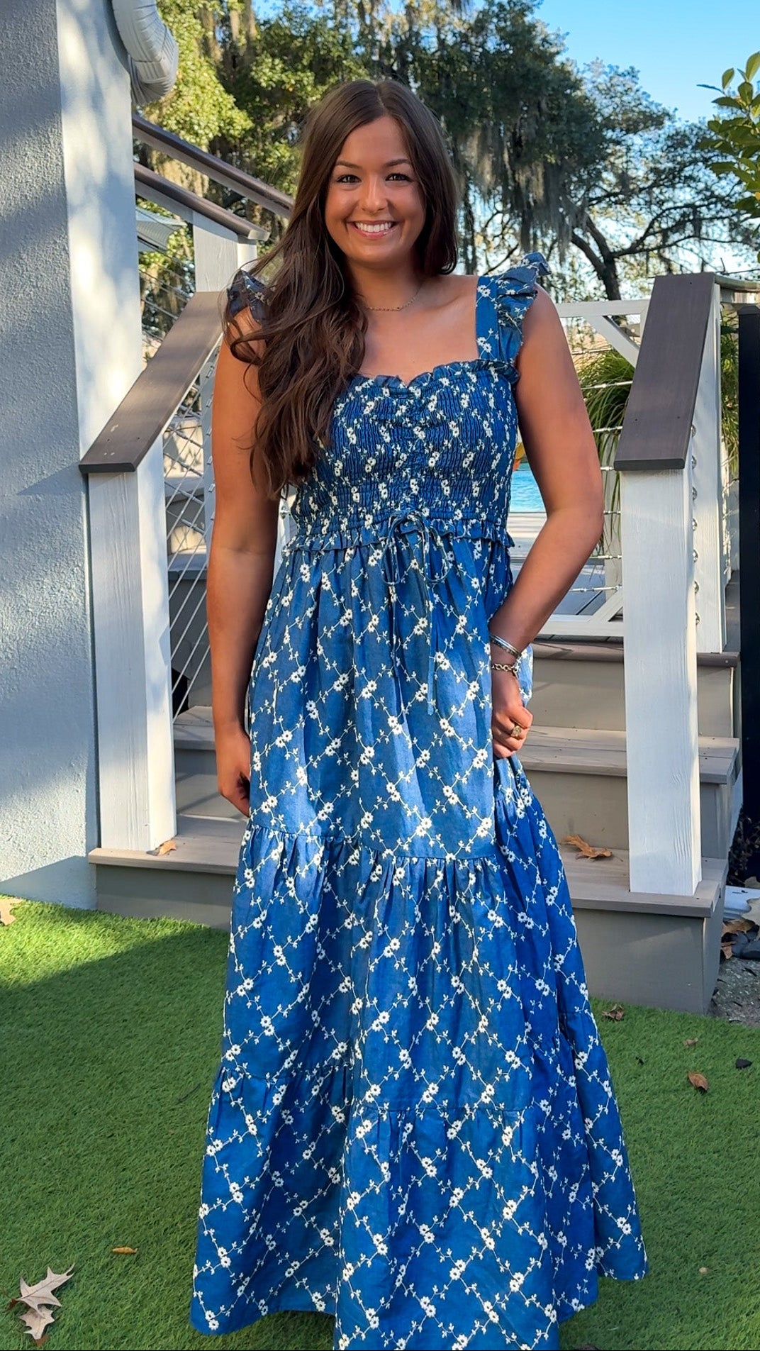 Denim blue and off-white floral tiered maxi dress with smocked bodice and flutter straps.