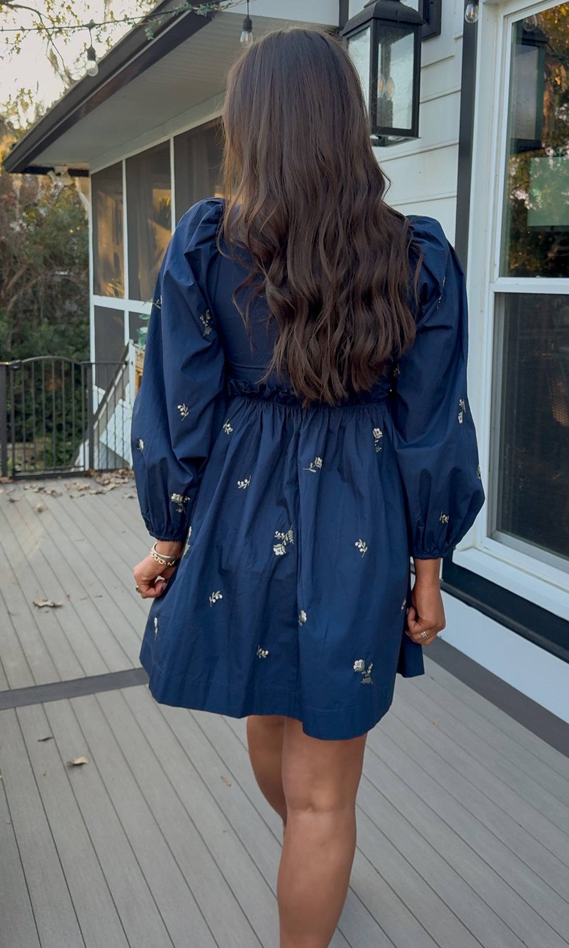 Navy long sleeve babydoll mini dress with floral embroidery detail and relaxed silhouette.