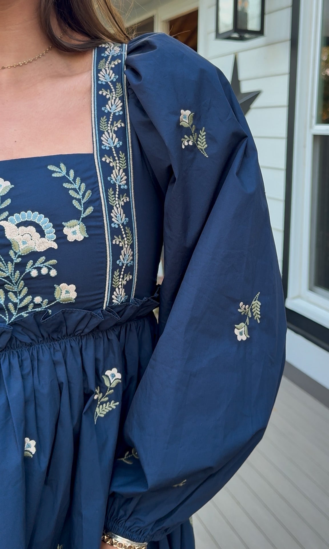 Navy long sleeve babydoll mini dress with floral embroidery detail and relaxed silhouette.