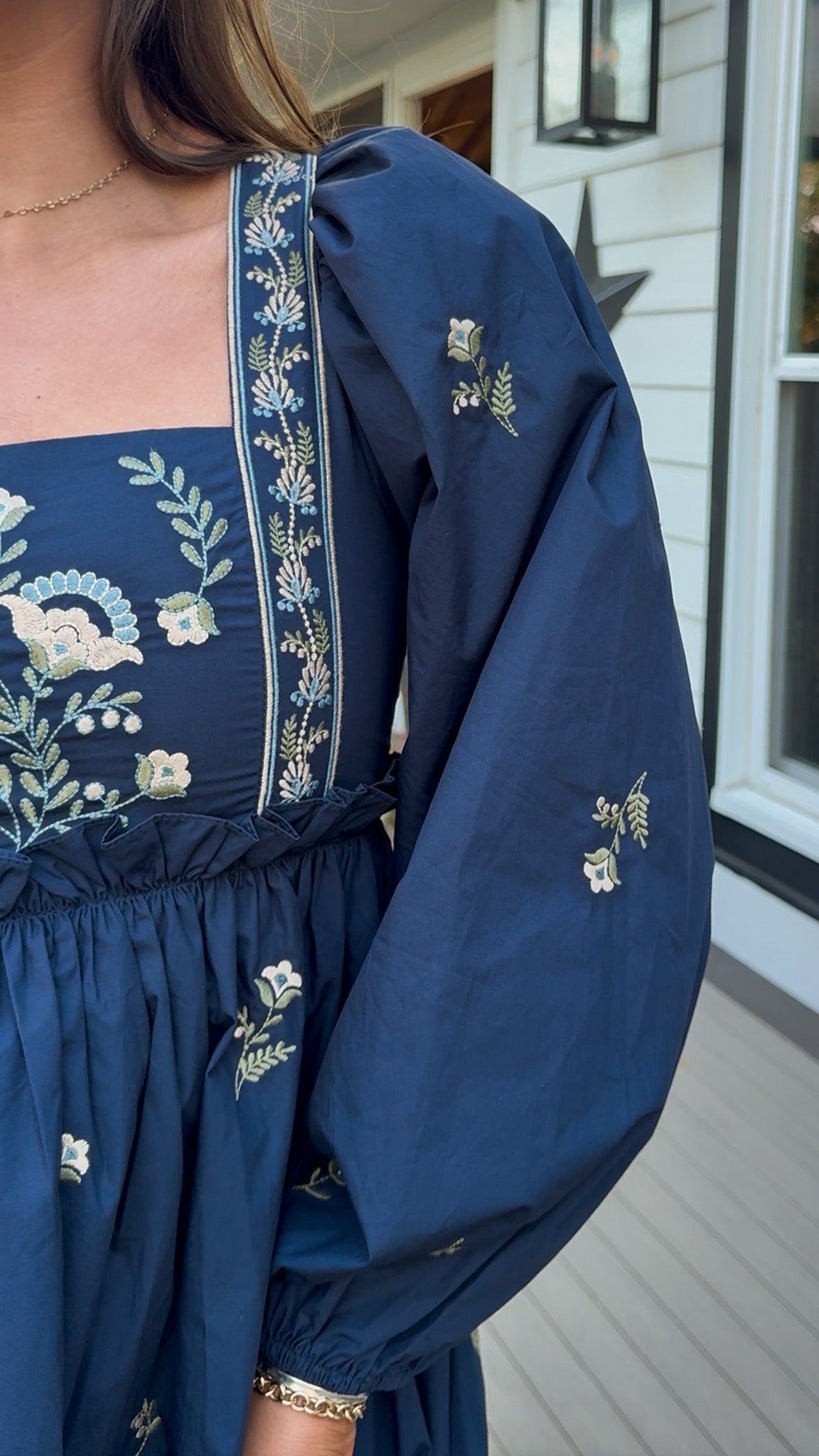 Navy long sleeve babydoll mini dress with floral embroidery detail and relaxed silhouette.