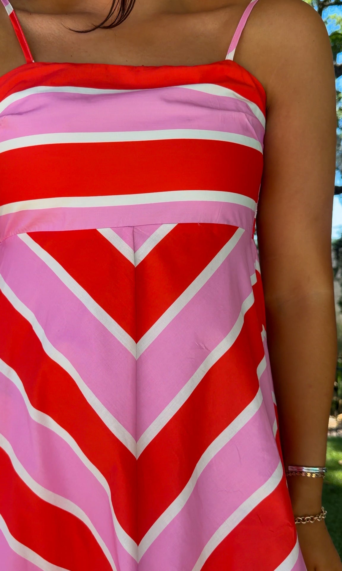 Person wearing a red and pink striped dress with a blurred background