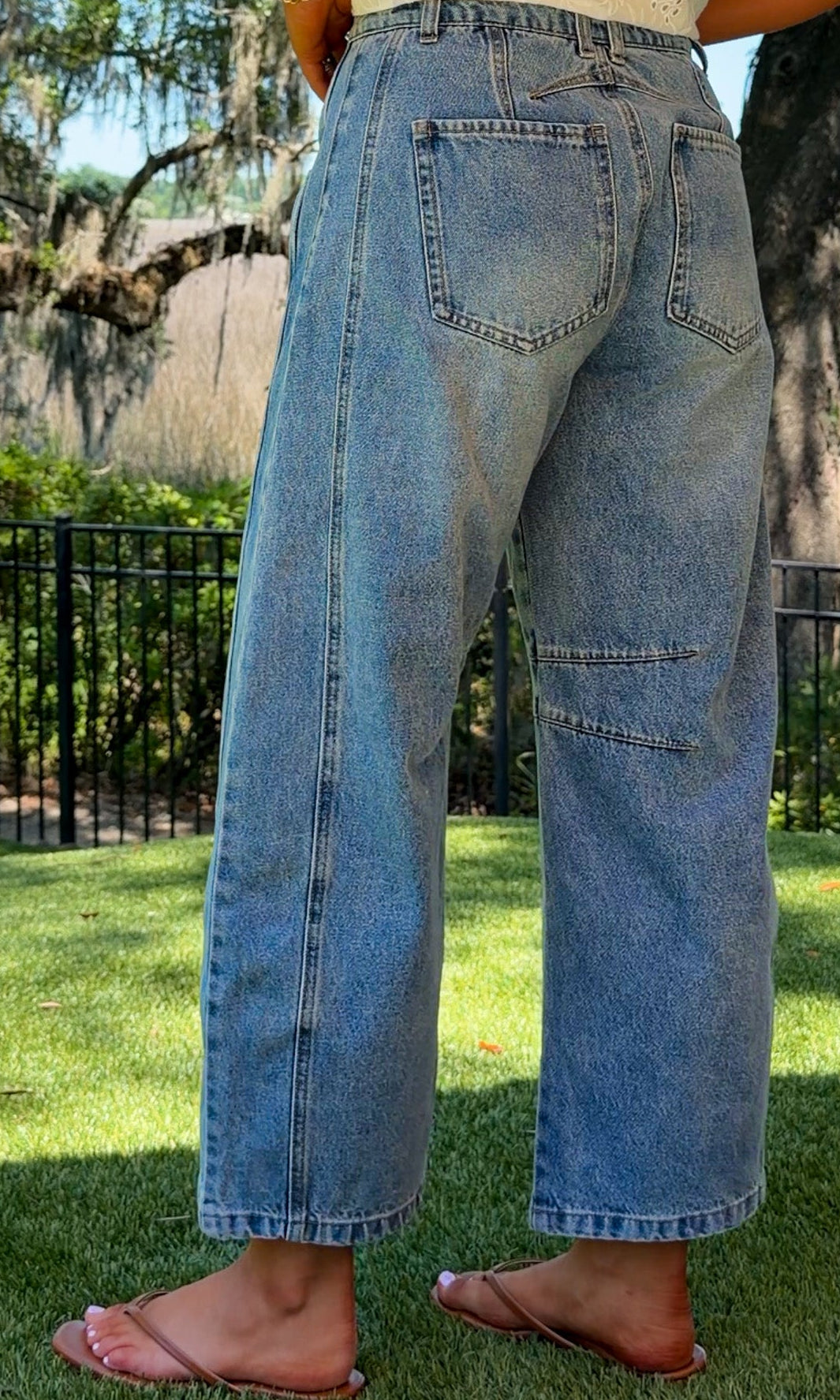 Person wearing blue jeans standing on grass with trees in the background