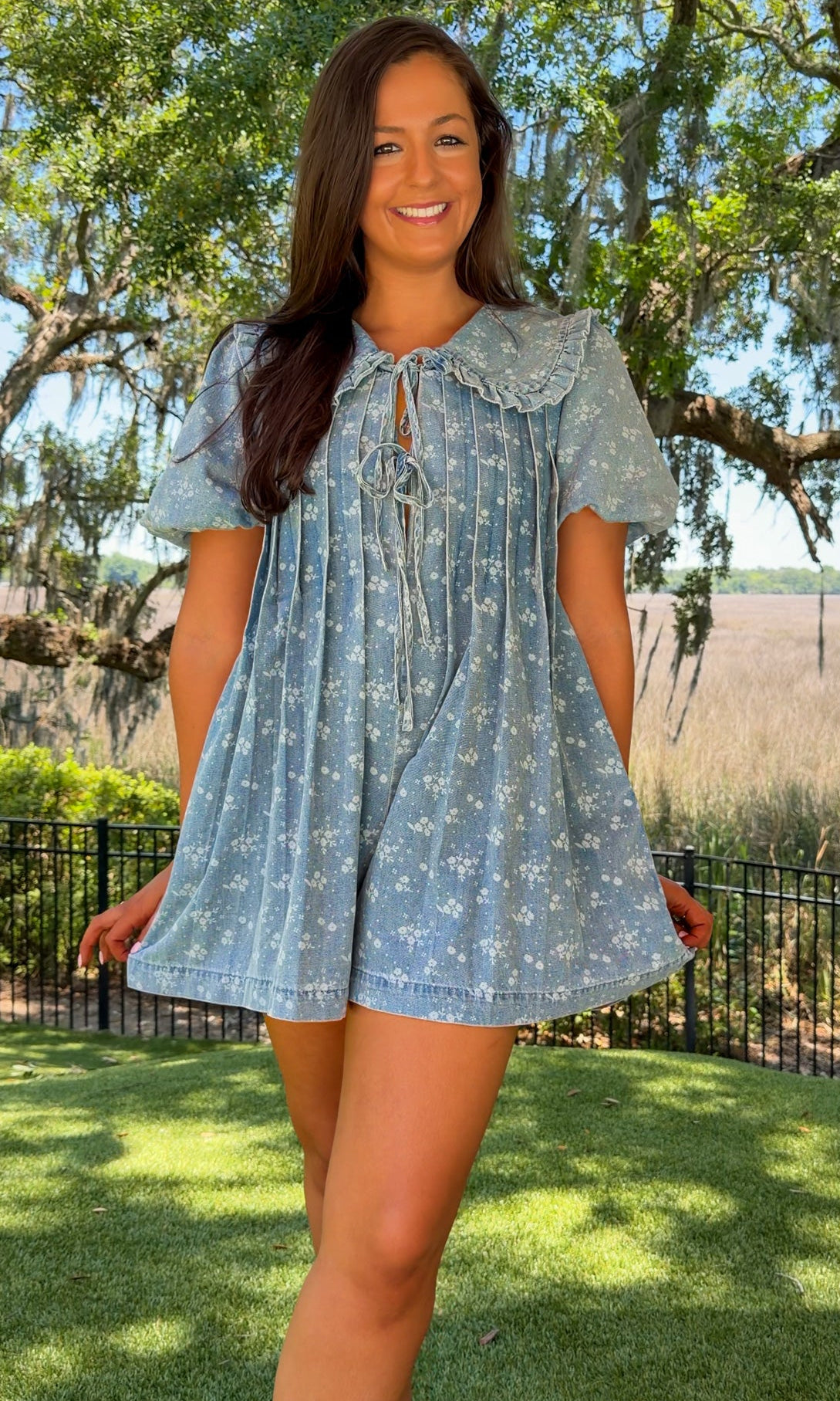 Woman wearing a blue dress with a floral pattern in an outdoor setting