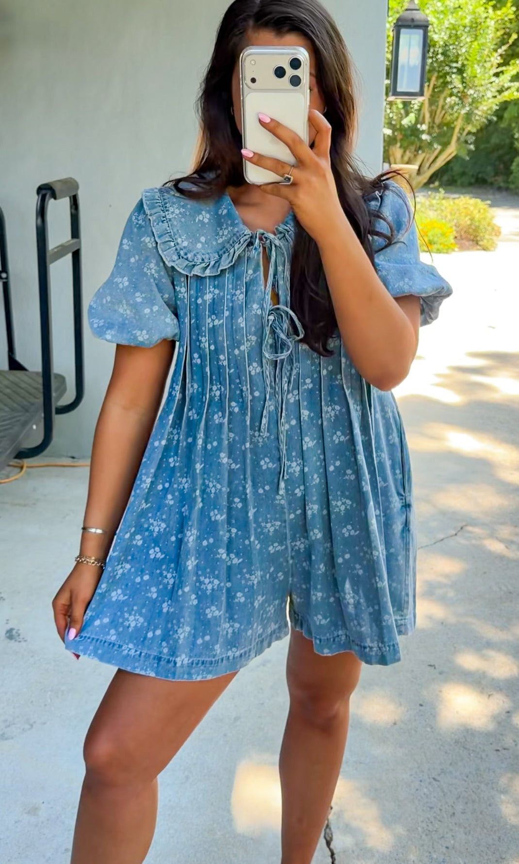 Woman taking a mirror selfie wearing a blue dress with white floral pattern.