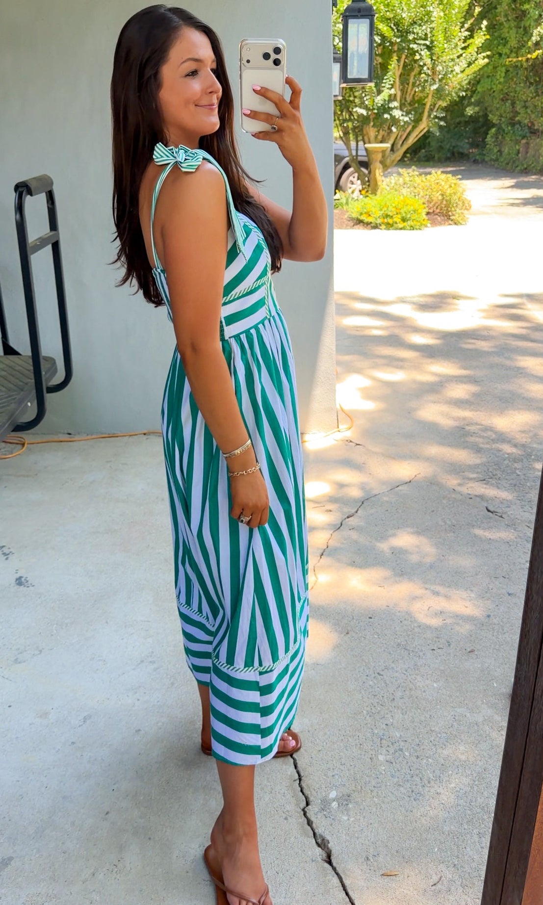 Woman taking a selfie wearing a green and white striped dress outdoors.