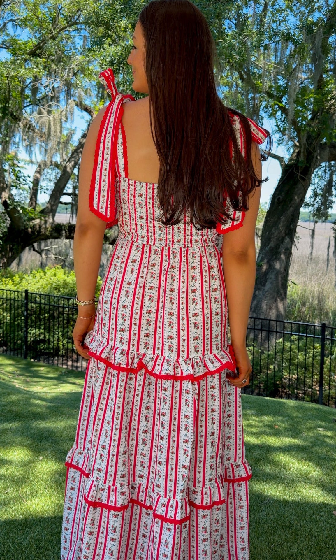 Woman wearing a red and white dress with ruffled sleeves in an outdoor setting.