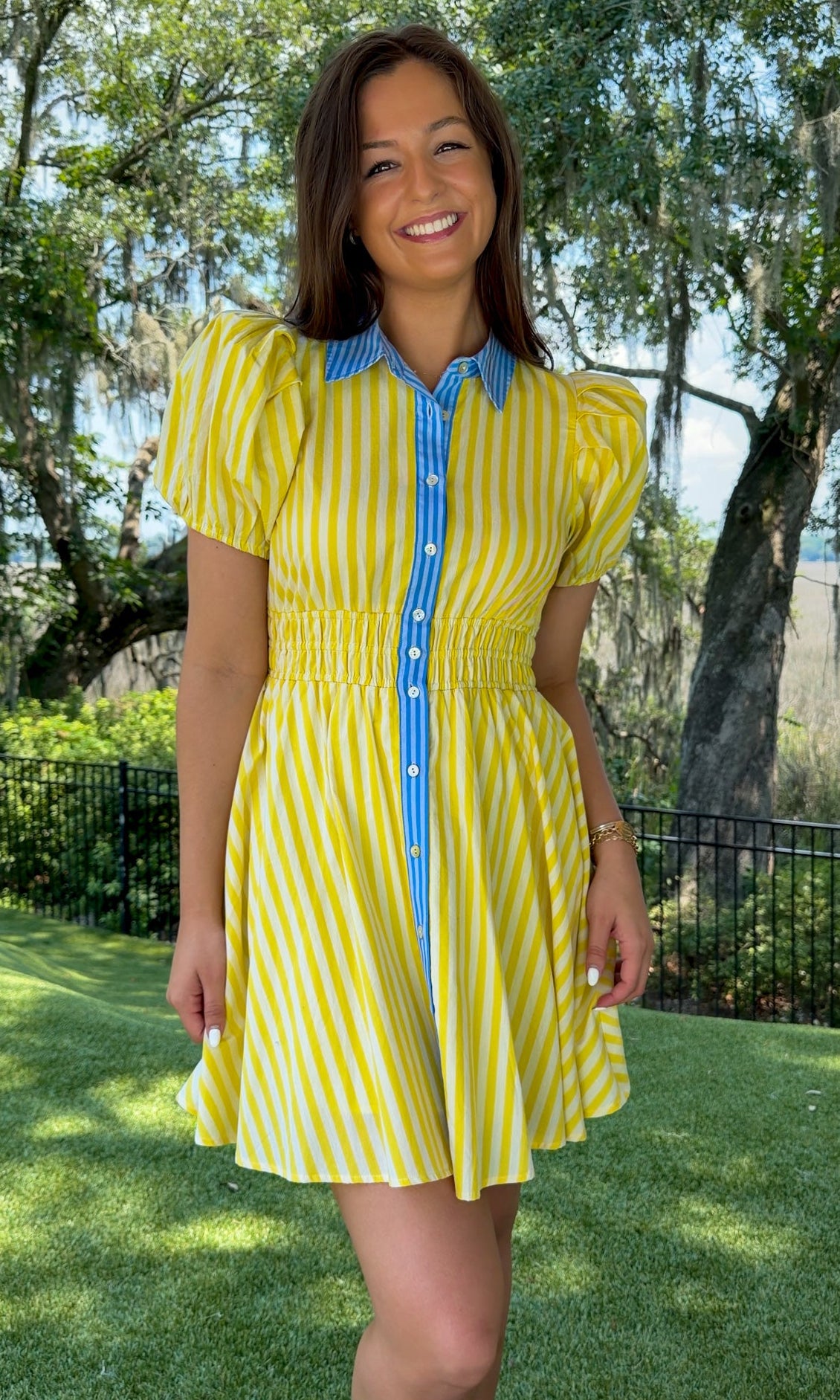 Yellow and ivory striped mini dress featuring a contrast blue collar and button placket, short puff sleeves, a smocked waist, side pockets, and a lightweight lined silhouette.